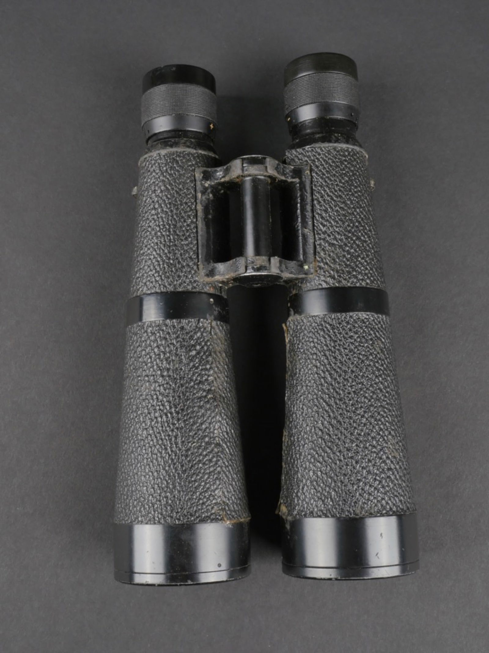 Jumelles 10X 50. 10 x 50 binoculars.: Jumelles 10 x 50. Revetement noir, partiellement abime. Optique claire et graduee. Marquages Dienstglas 10x50, fabrication BMJ 526712. A noter une certaine usure et patine de la piece. Etat II+. Binoc