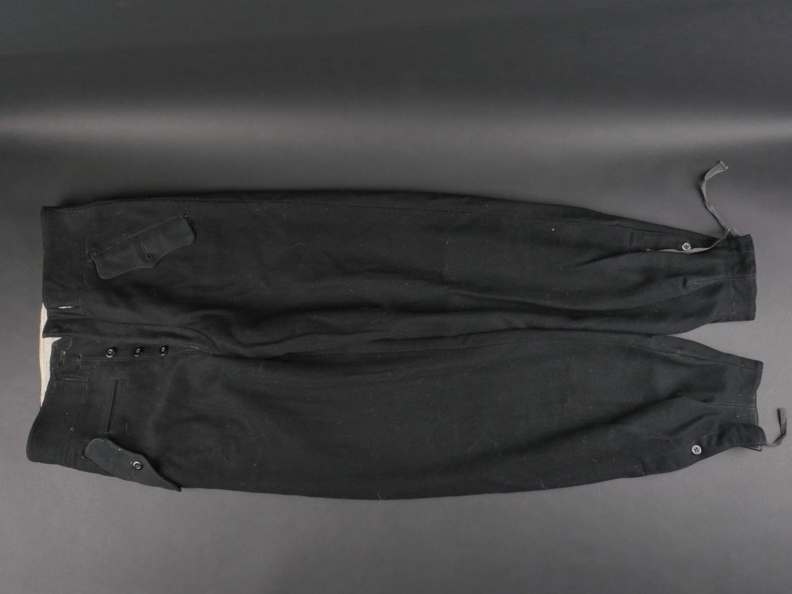 Pantalon Panzer. Panzer trousers.: Pantalon Panzer. En drap noir. Tous les boutons sont presents. Bas des jambes fermant par un bouton et un lacage. Poches de hanche a rabat, fermant par un seul bouton. Ceinture manquante. Interieur do