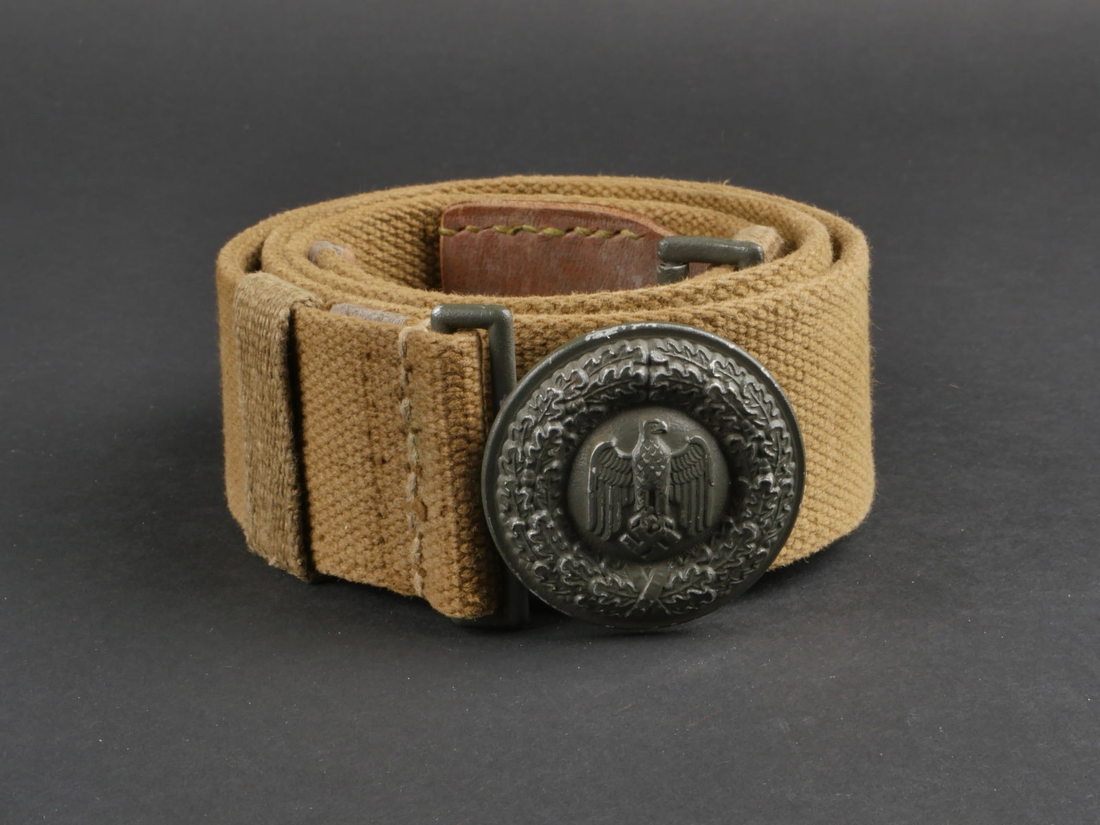 Ceinturon officier AK. Afrikakorps officer belt.: Ceinturon d'officier Afrikakorps. Ceinturon en toile, taille 95, patte de reglage en cuir marron. Reste de tampon illisible sur le ceinturon. Les deux passants en toile sont presents. Boucle a deux ar