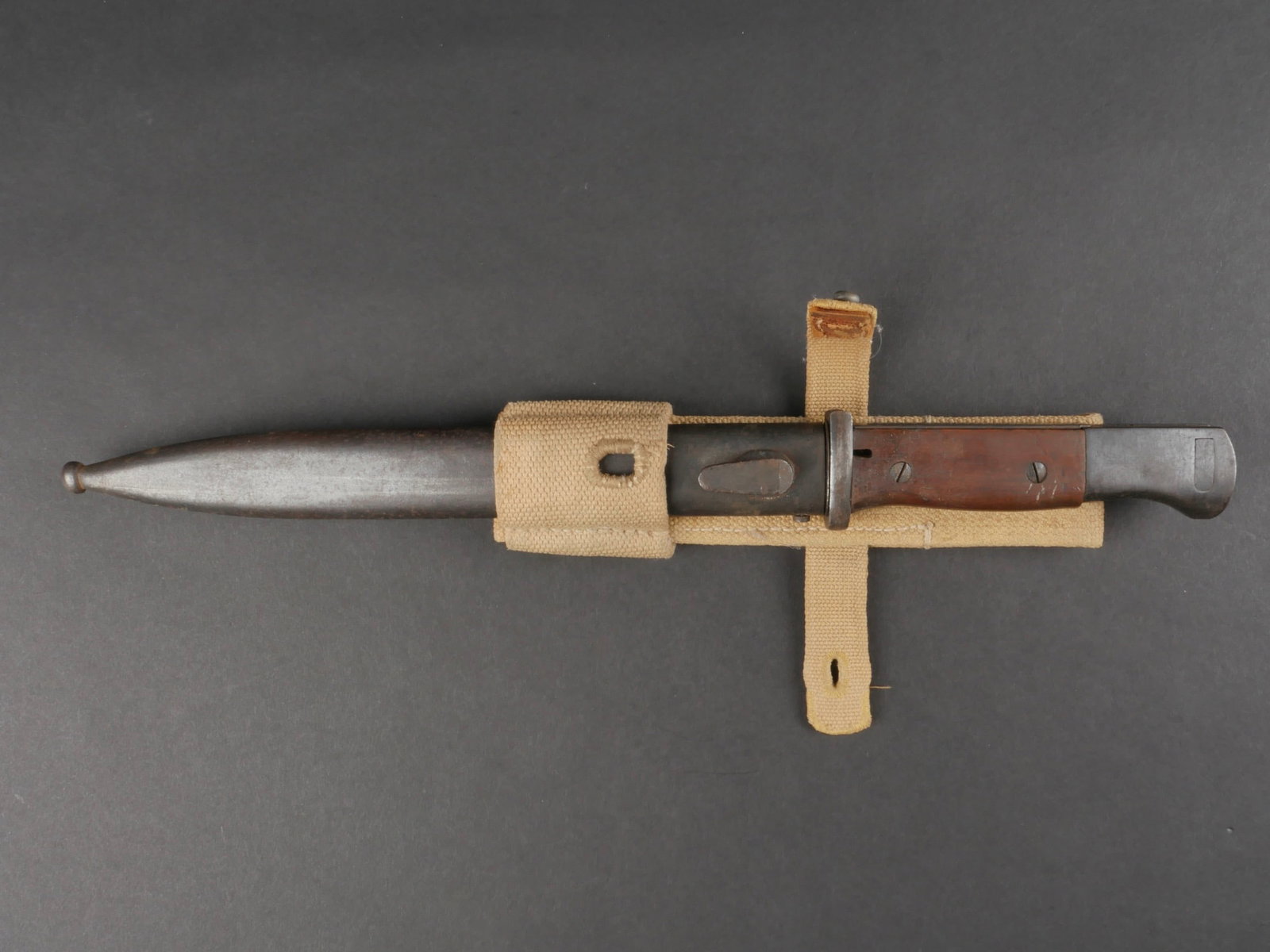 Baionnette 98K et gousset en toile. 98K bayonet.: Baionnette 98K et gousset en toile. Garnitures en metal, dans leur couleur d'origine a 40%. Plaquettes en bois marron, maintenues par deux vis. Lame dans sa couleur d'origine a 80%, sans marquages vis