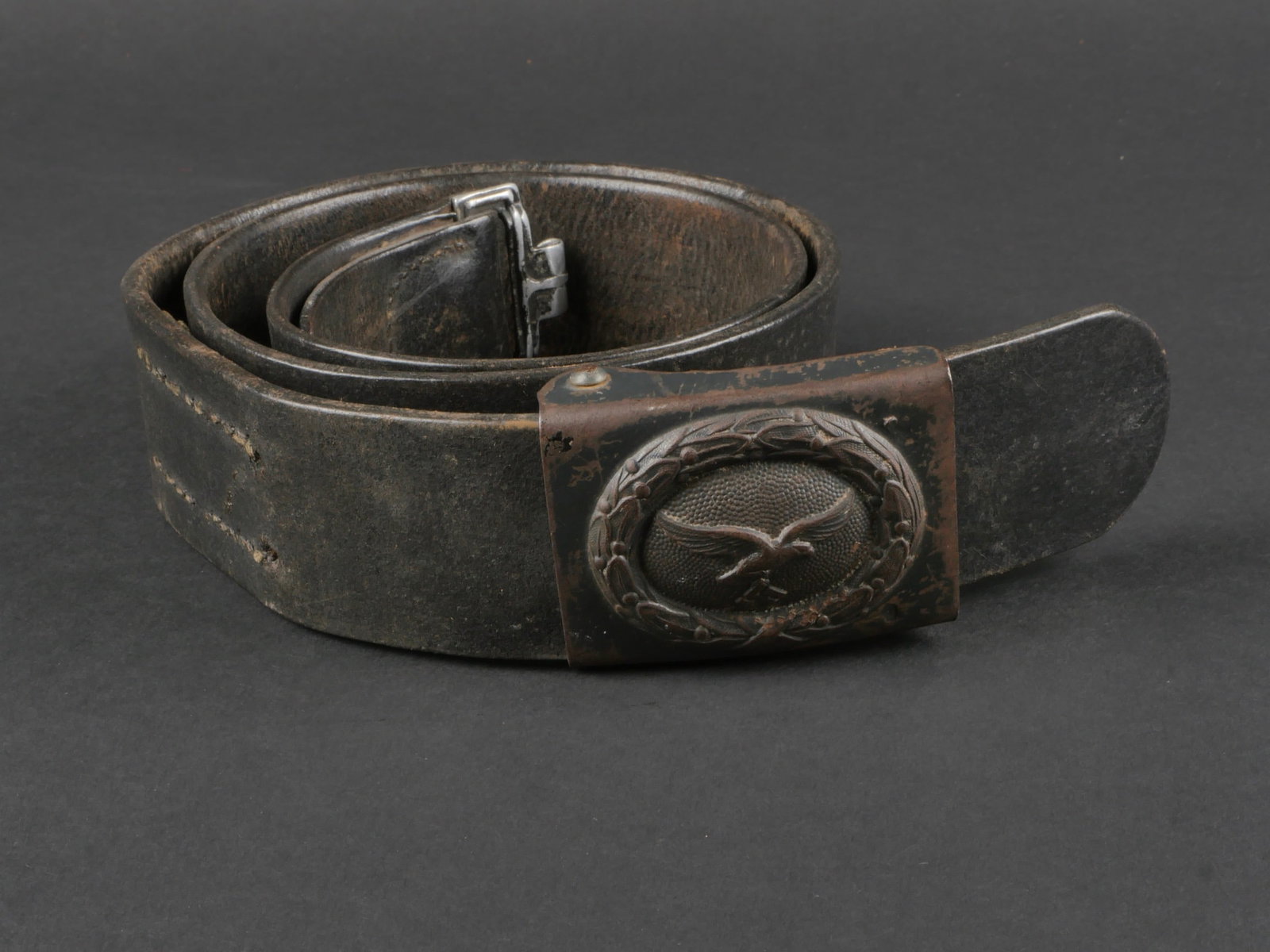 ceinturon de la LW. Luftwaffe belt.: ceinturon de la Luftwaffe. ceinturon en cuir noir, bouclerie en metal, reste de marquages illisibles. Patte de reglage presente, mais visiblement recousue. Taille 100. Boucle de ceinturon de la Luftwa