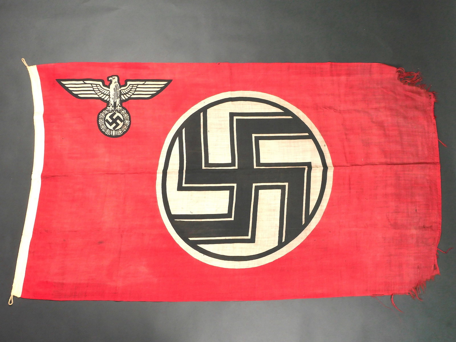 Drapeau allemand. German flag.: Drapeau allemand. En tissu coton rouge, biface. Modele imprime. Aigle et insigne national. Les cordelettes d'attache au mat sont presentes. Marquages Reichsdflg. Dimensions 100 x 170 cm. Une partie du