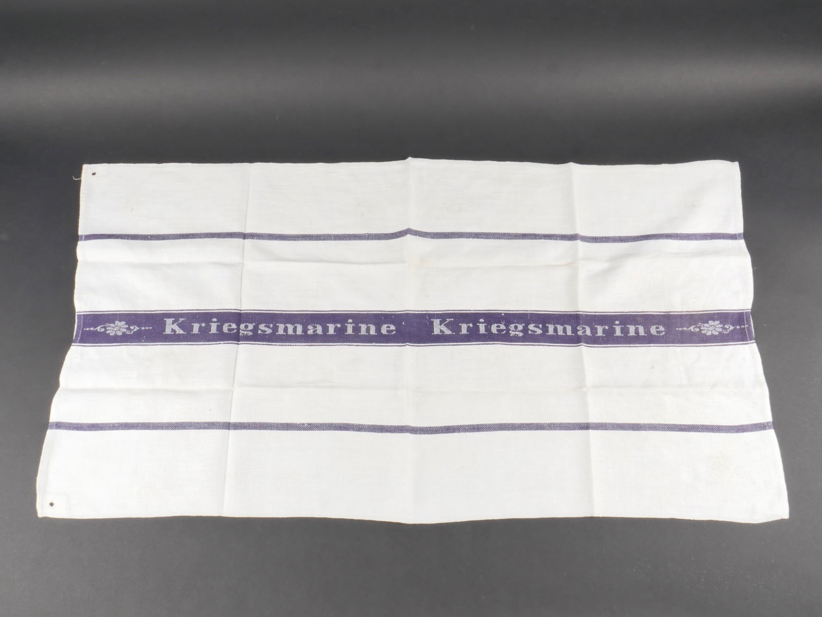 Serviette Kriegsmarine. Kriegsmarine tovel.: Torchon de la Kriegsmarine. En tissu coton blanc, bandes bleues. La bande centrale est marquee Kriegsmarine. A noter une legere usure et patine de la piece, ainsi que de discretes taches. Etat II+. Kr