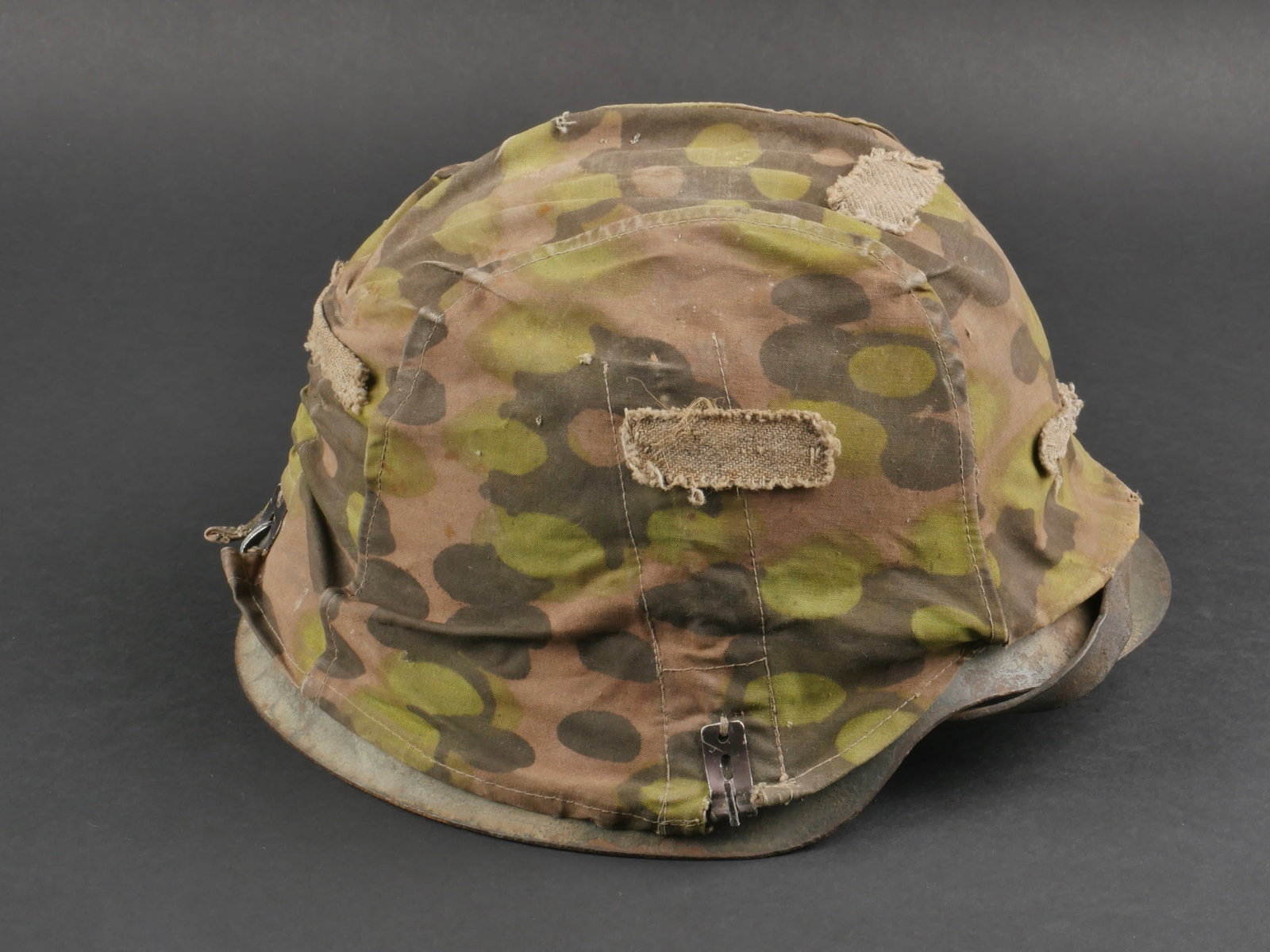 couvre casque SS precoce. Early SS helmet cover.: couvre casque camoufle SS. Modele precoce. En tissu camoufle reversible ete et automne. Les crochets sont presents. Les ressorts sont visibles sous la toile. Seul le ressort arriere est encore souple.