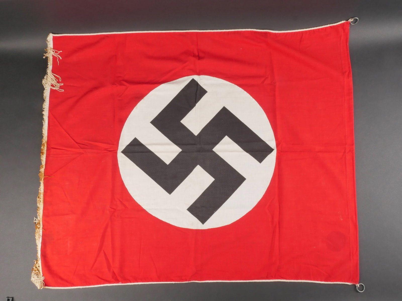 Drapeau de tribune allemand. German tribune flag.: Drapeau de tribune allemand. En tissu coton rouge. Insigne national imprime et rapporte. Mono face. Deux anneaux metalliques permettant la fixation du drapeau a la tribune. Frange au bas du drapeau. L