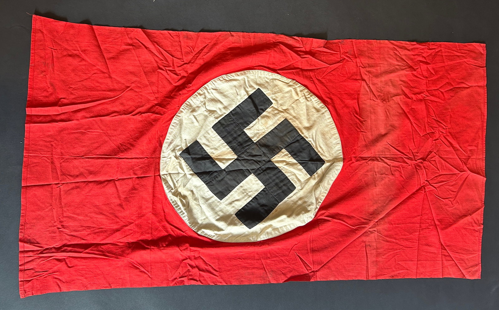Drapeau allemand. German flag.: Drapeau allemand. En tissu coton rouge. Insigne national realise en plusieurs parties et rapporte. Biface. Sans marquages visibles. Dimensions 73 x 138 cm. A noter une certaine usure et patine de la p