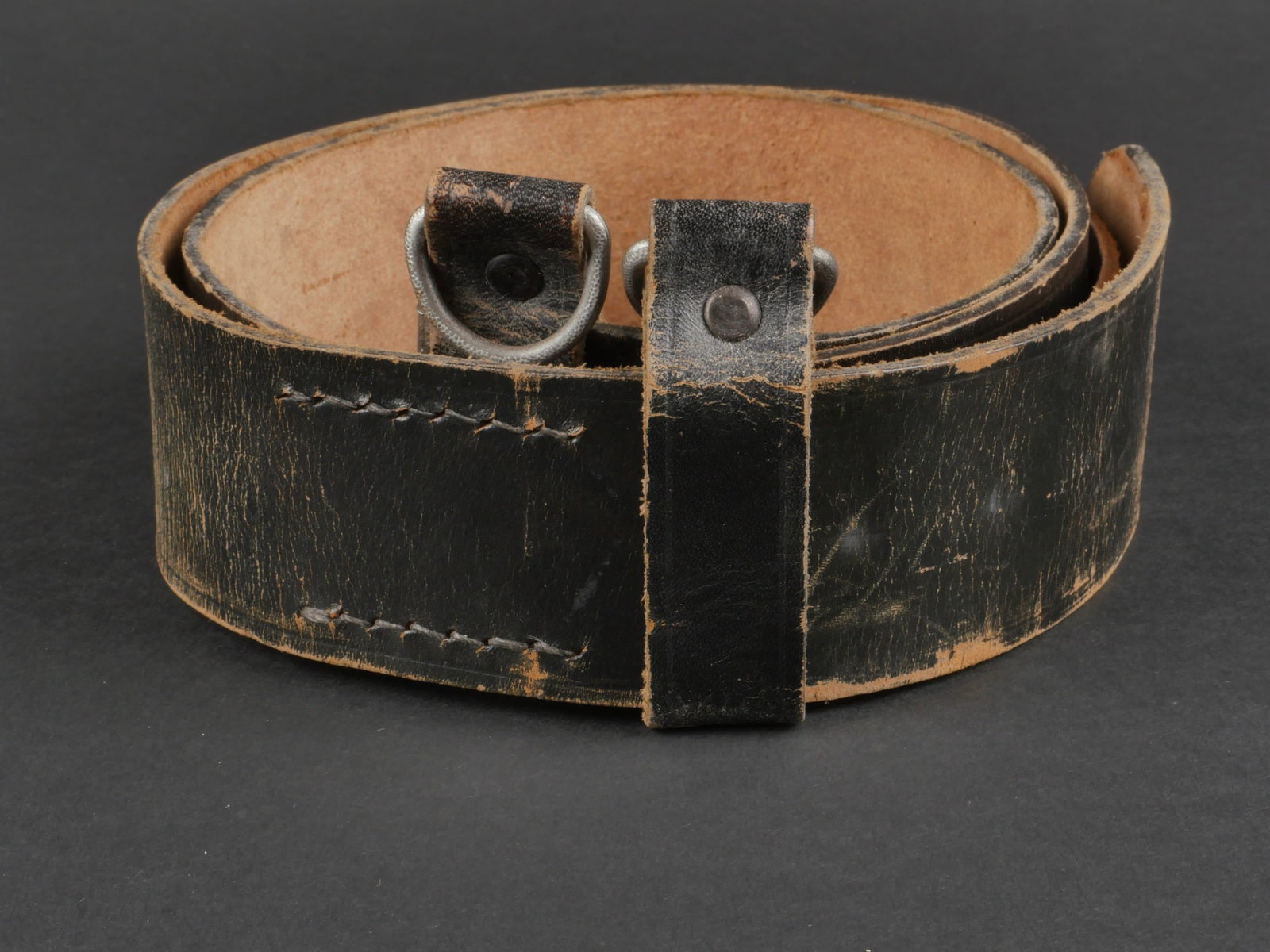 ceinturon allemand. German belt.: ceinturon allemand. En cuir noir lisse. Quelques marques d'usures visible. Bouclerie en metal. Tampon du fabricant Karl Heller. La patte de reglage en cuir fauve est presente et cousue d'origine. Deux