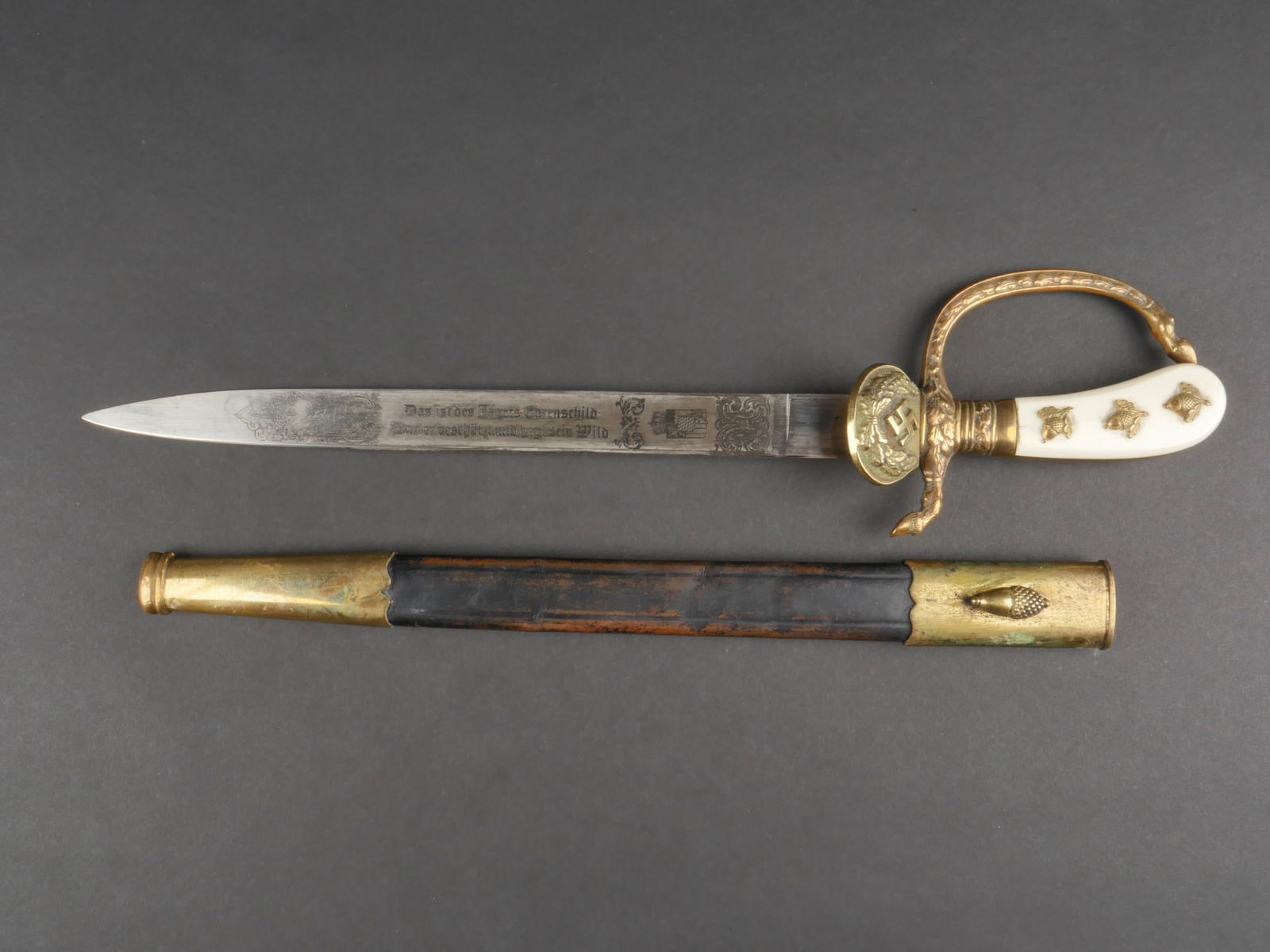 Dague de chasse. Hunting dagger.: Dague de chasse. Modele dit de luxe. Plaquettes de couleur blanche, presentant quelques fissures. Trois glands et feuilles de chene fixes au niveau des plaquettes. Decors a feuilles de chene. Garde fi