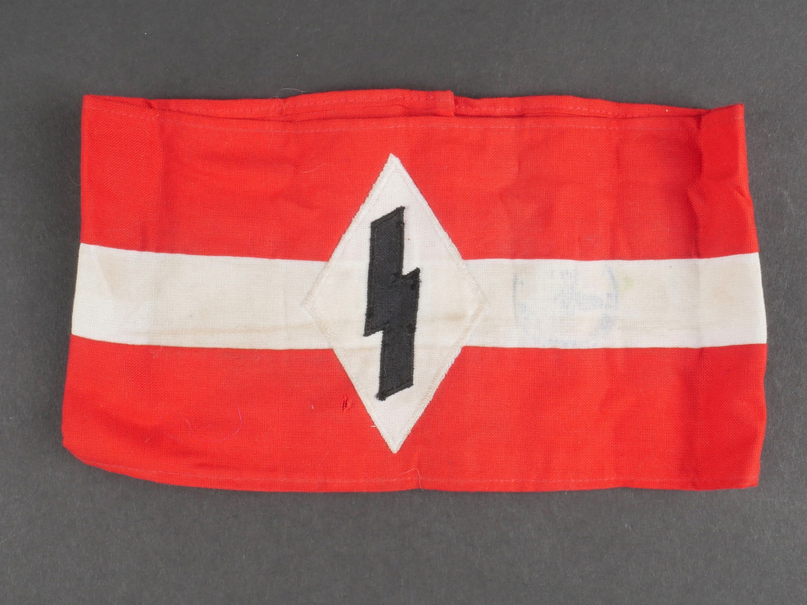 Brassard DJ. Deutsche Jungvolk armband.: Brassard Deutsche Jungvolk. En tissu coton rouge et blanc. Insigne DJ rapporte. Reste d'un tampon illisible. Sans marquages visibles. A noter une certaine usure et patine de la piece, ainsi que quelqu