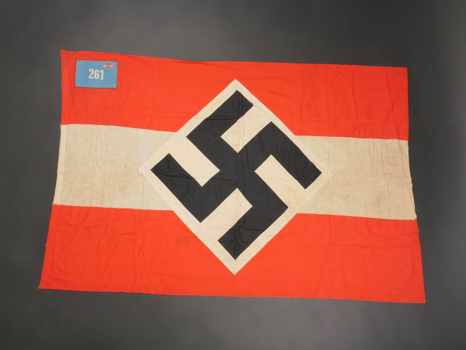 Drapeau du DLV. German DLV flag.: Drapeau du DLV. En tissu coton rouge et blanc. Biface. Insigne national rapporte. cartouche en drap bleu ciel, bordure d'une tresse or, brodee du chiffre 261 et de l'insigne du DLV. Toutes les attache
