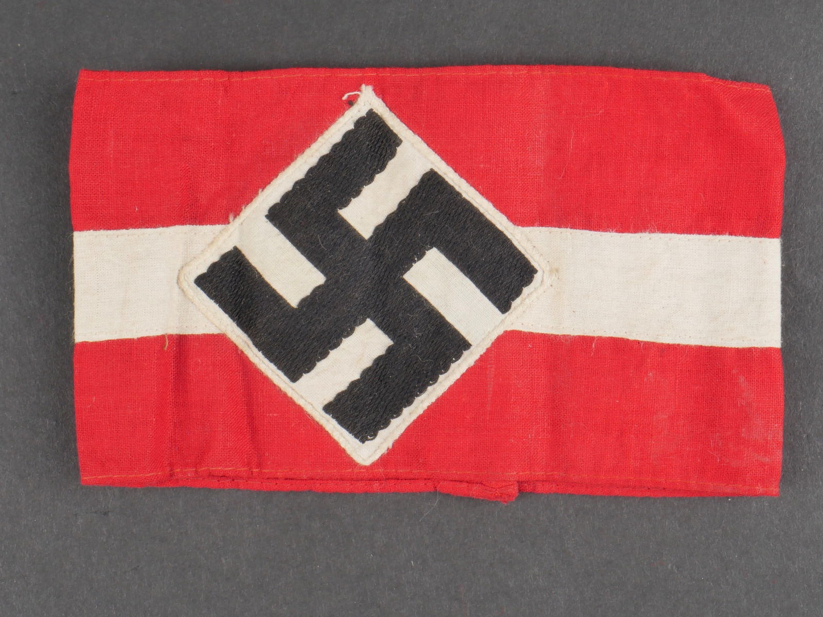Brassard HJ. Hitlerjugend armband.: Brassard Hitlerjugend. En tissu coton rouge et blanc. Insigne national tisse et rapporte. Traces d'une etiquette RZM au dos. celle-ci est absente. A noter une certaine usure et patine de la piece, ain
