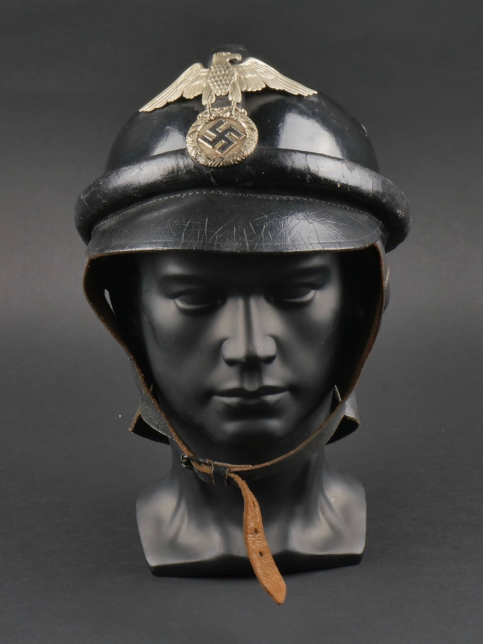 casque NSKK. NSKK helmet.: casque NSKK. En fibre noir, quatre Å“illets d'aeration. Plusieurs bourrelets de protection en cuir noir. Aigle metallique tete a gauche du premier type. Les insignes n'ont pas ete demontes afin de 