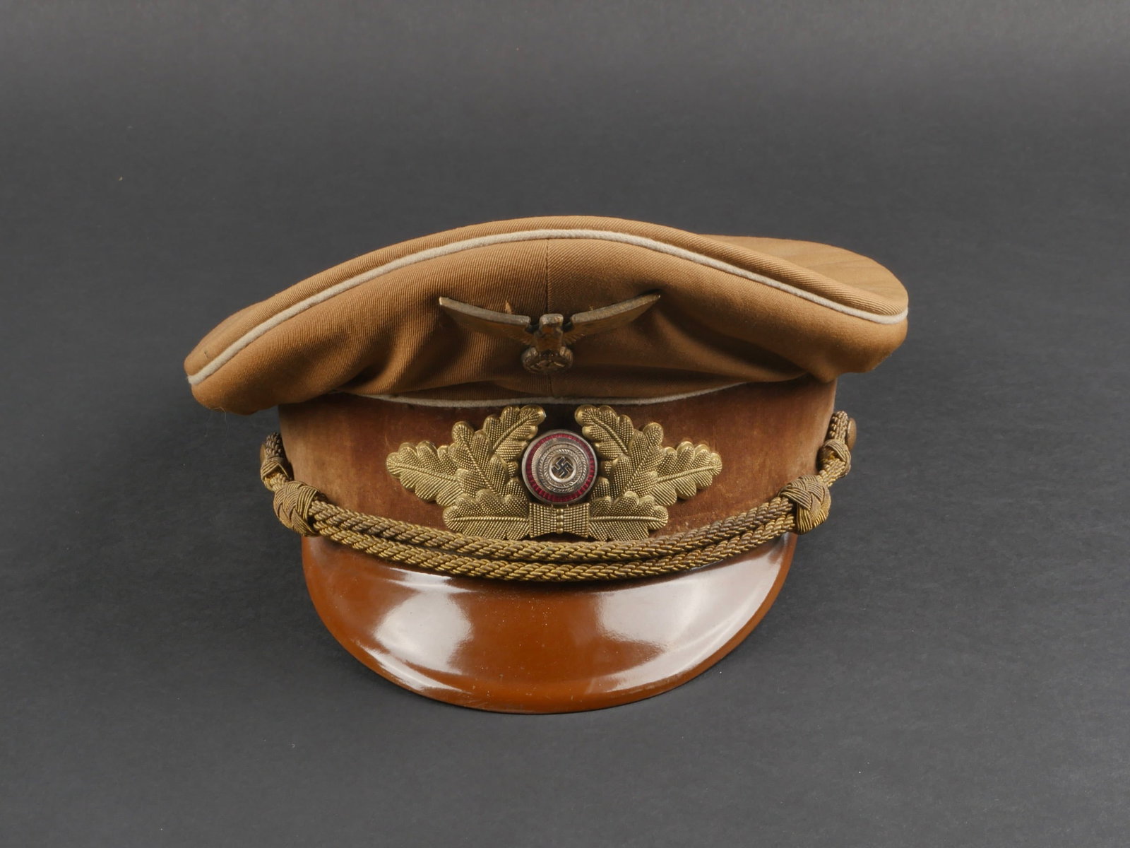 casquette Politischer Leiter. Politischer Leiter cap.: casquette Politischer Leiter. En tissu kaki. Triple lisere blanc. Bandeau en velours marron. Insignes metalliques. Les insignes n'ont pas ete demontes afin de verifier les attaches. Fausse jugulaire c