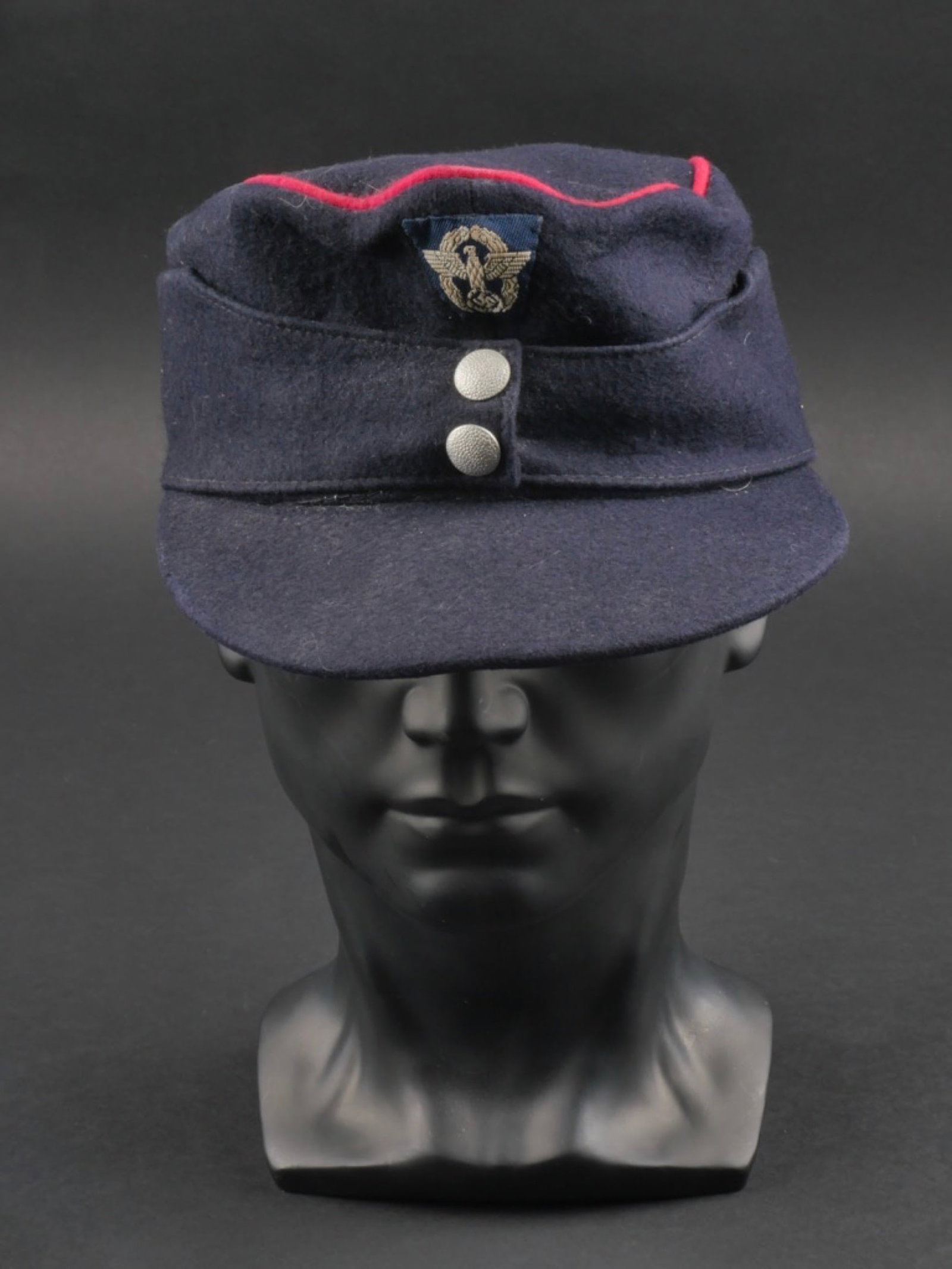 casquette Feuerschutzpolizei. Feuerschutzpolizei cap.: casquette Feuerschutzpolizei. En drap bleu marine. Lisere rose faisant le tour de la coiffure. Rabat fermant par deux boutons greneles argent. Insigne Polizei tisse sur fond bleu marine, monte machine