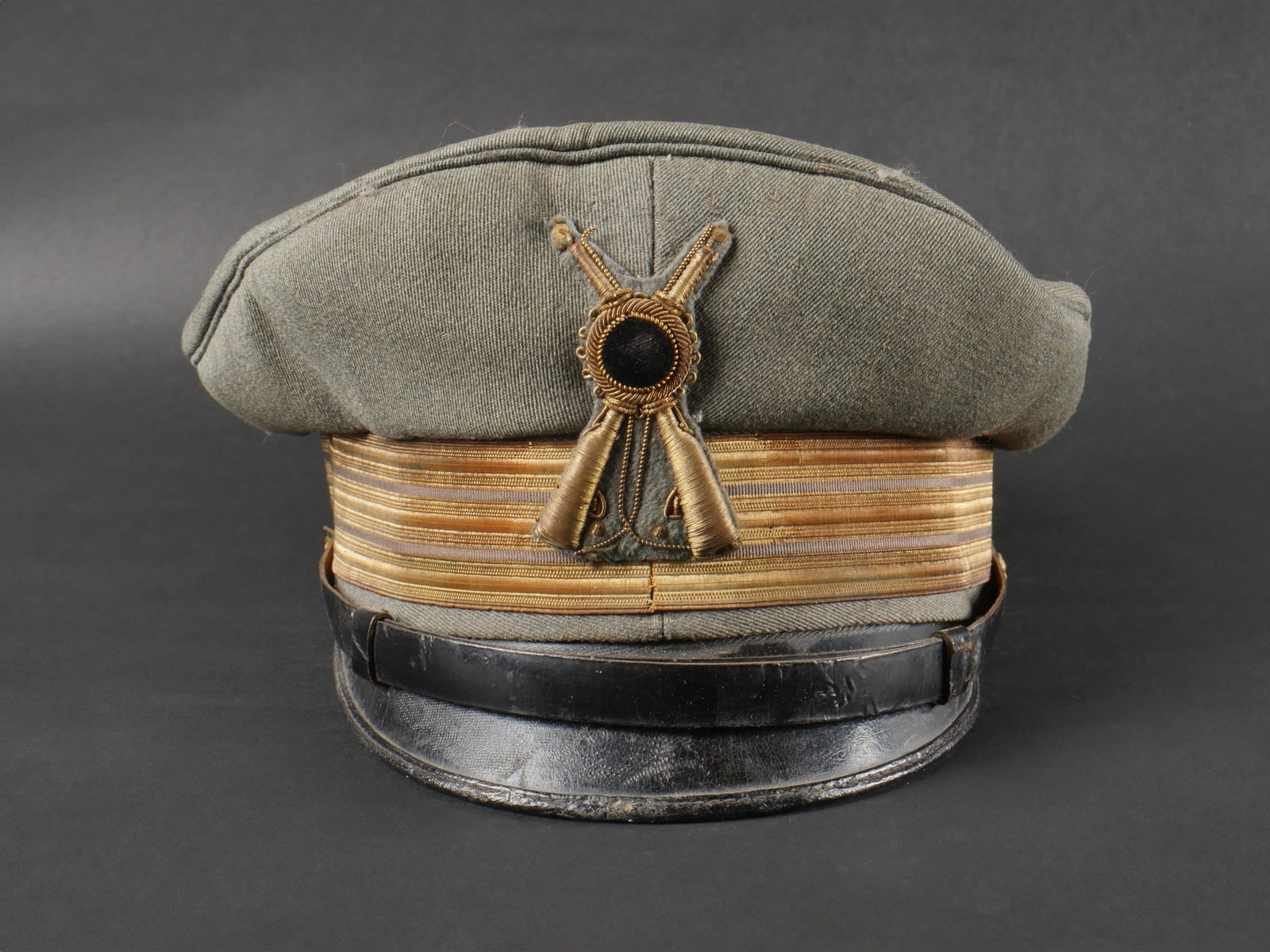 Casquette de capitaine d’infanterie. Infantry captain s cap.: Casquette de capitaine d’infanterie. En drap gris vert avec insigne frontal dont on a ote la couronne royale, grades de capitaine sur le bandeau, interieur en satinette grise, logo commerciale du fa