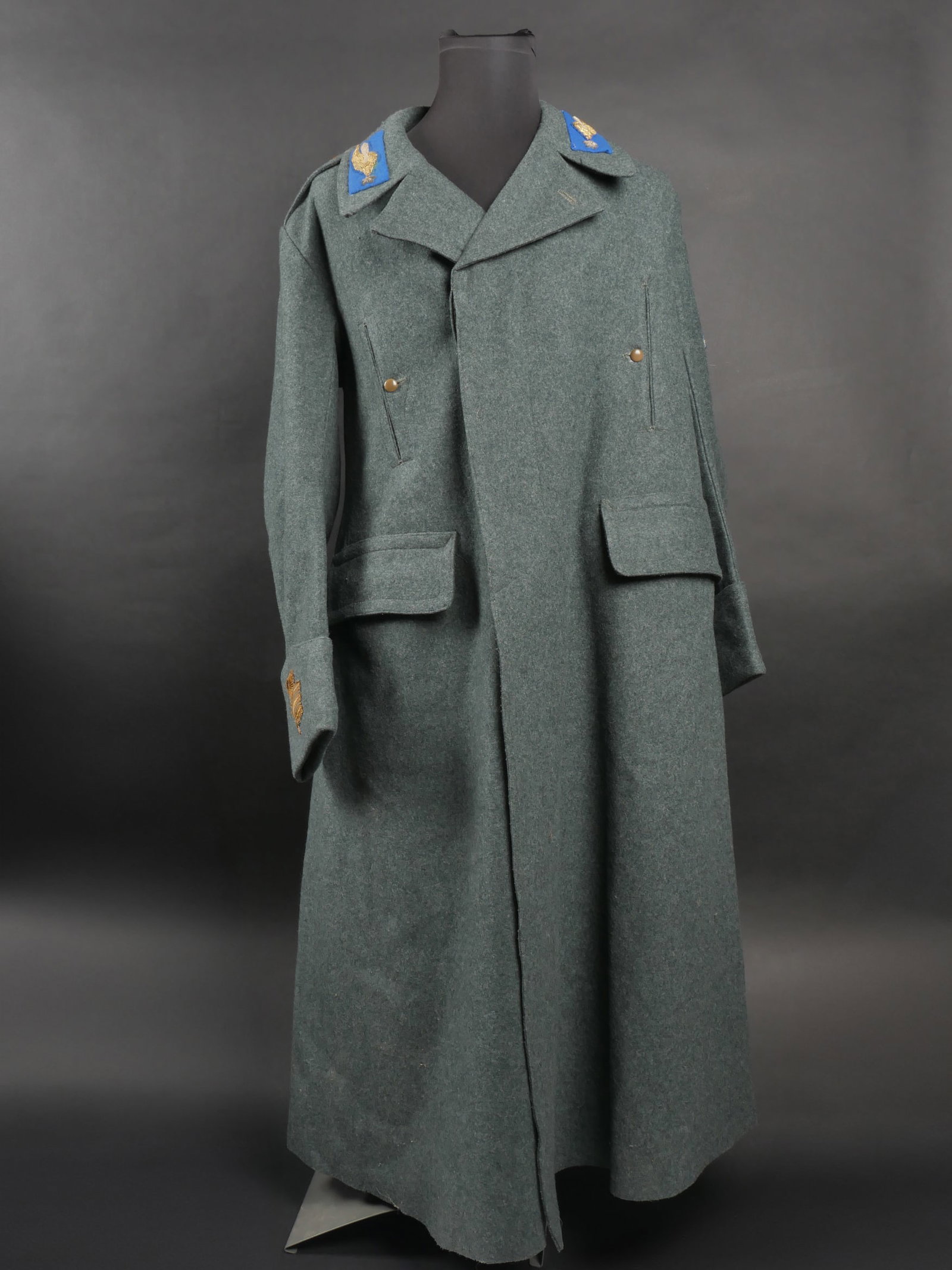 Capote de capitaine des troupes parachutistes. Captain s parachute capote.: Capote de capitaine des troupes parachutistes. En drap gris vert avec mostrines et pattes de col en cannetille doree sur fond bleu des troupes parachutiste, sur la manche gauche se trouve un brevet de