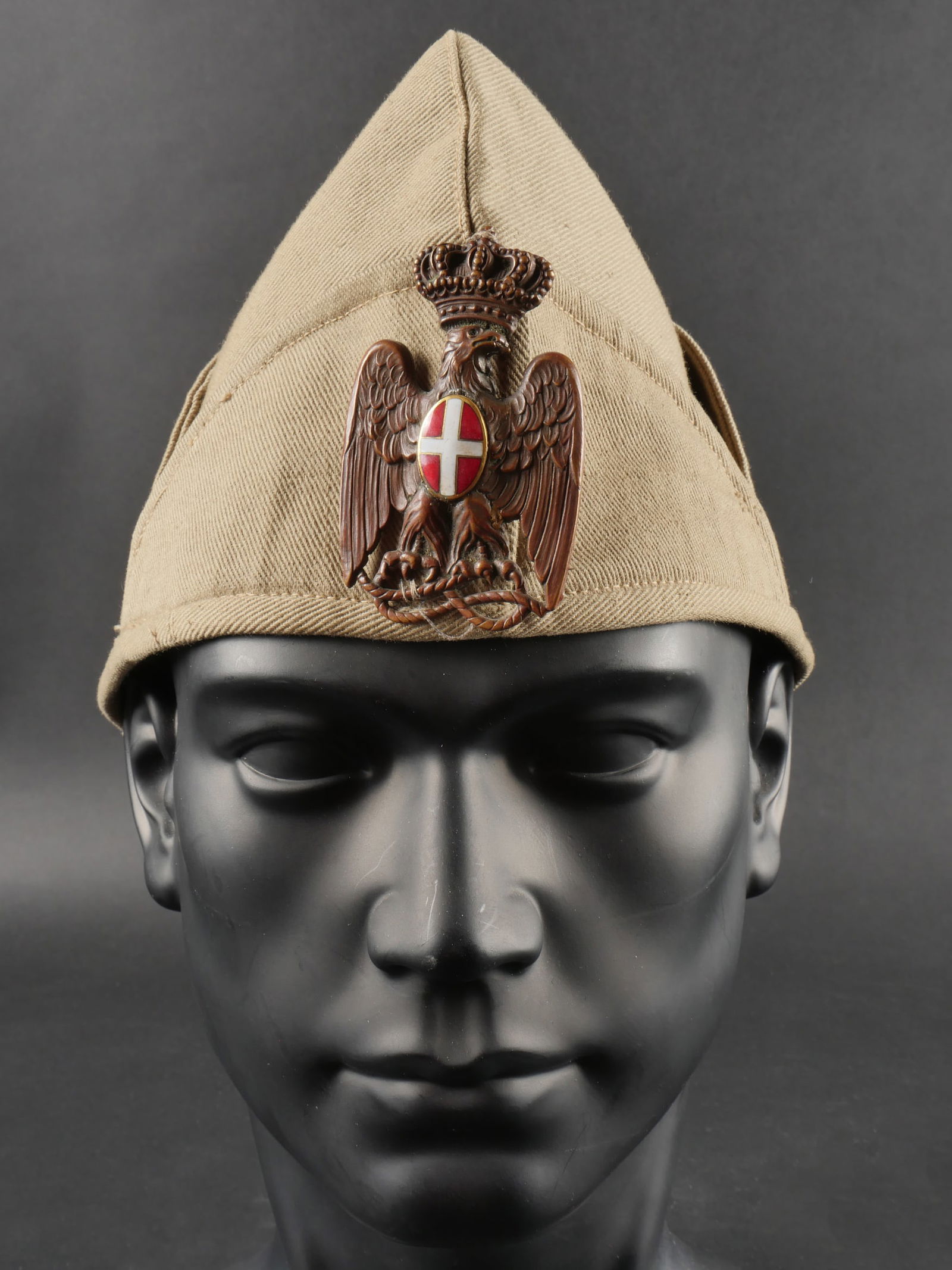 Bustina troupe de la PAI. Bustina PAI troupe.: Bustina troupe de la PAI. Au modele de 1934 en toile coloniale avec son insigne metallique frontal. La PAI etait la Police de l’Afrique Italienne. Etat II-. PAI troop bustina. 1934 model in colonial