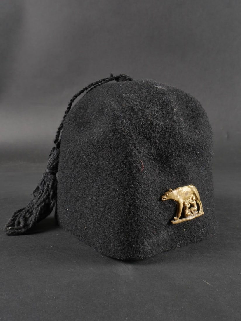 Coiffure de mouvement de jeunesse fasciste. Fascist youth movement headdress.: Coiffure de mouvement de jeunesse fasciste. Comportant une coiffure de jeune garcon des Fils de la Louve, en feutre, avec son pompon et son insigne metallique. Etat II-. Fascist youth movement headdre