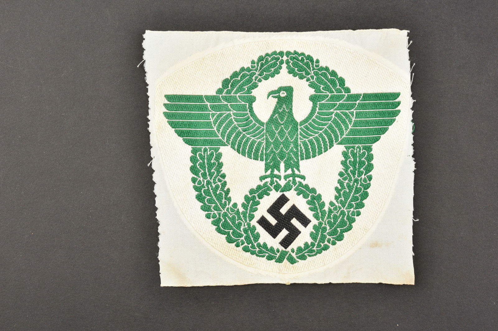Insigne de maillot de sport Polizei. Polizei sports shirt badge.: Insigne de maillot de sport Polizei. Petit modele d aigle, tissage vert sur fond en tissu blanc. Jamais monte. A noter une certaine usure et patine de la piece, ainsi que quelques taches. Etat II+. Po