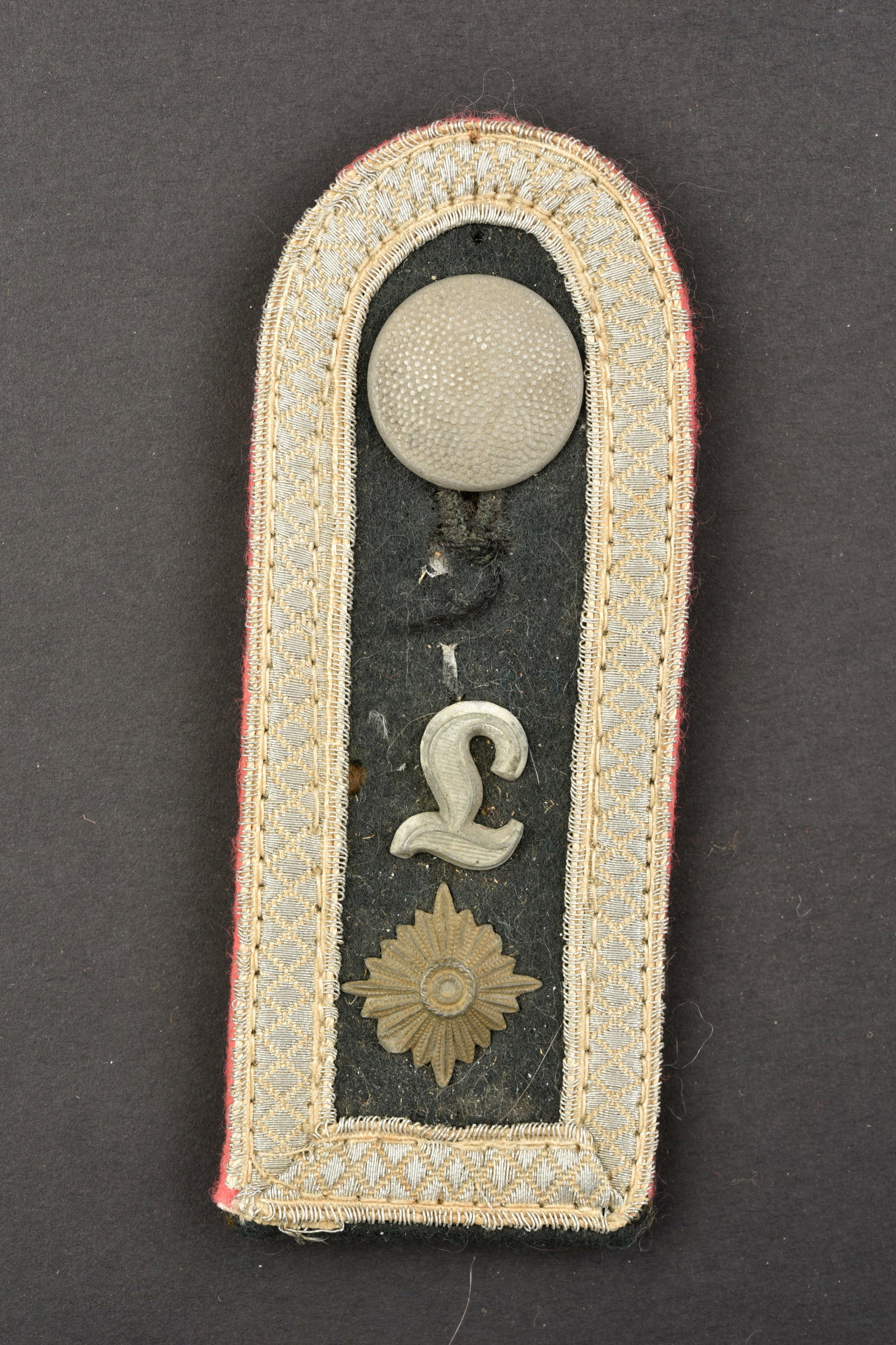 Patte d epaule Panzer Lehr. Panzer Lehr shoulder straps.: Patte d epaule Panzer Lehr. En drap couleur vert canard, lisere rose des unites de Panzer, grade de Feldwebel. Un bouton en metal grenele present. Dos de la piece double en drap marron. A noter une ce