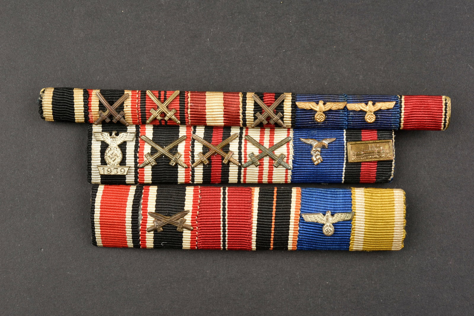 Barrette de ruban de decoration. Decorative ribbon bar.: Barrettes de rubans de decoration. Comprenant un barrette avec ruban de la croix de fer, de la medaille du front de l est, de la KVK avec glaive, ainsi que trois autres decoration, agrafe incomplete, 