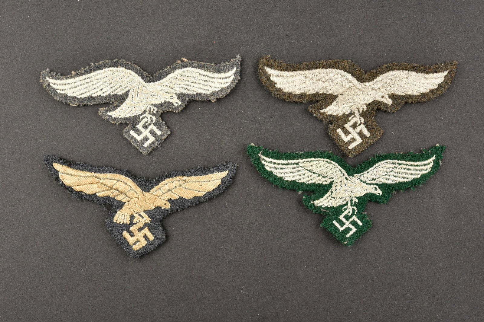 Aigles de poitrine LW. LW breast eagles.: Aigles de poitrine de la Luftwaffe. Comprenant un aigle brode sur fond gris/bleu. Un aigle brode monte sur drap marron. Un aigle tisse, fabrication bombee, sur fond en drap gris/bleu. Un aigle brode s