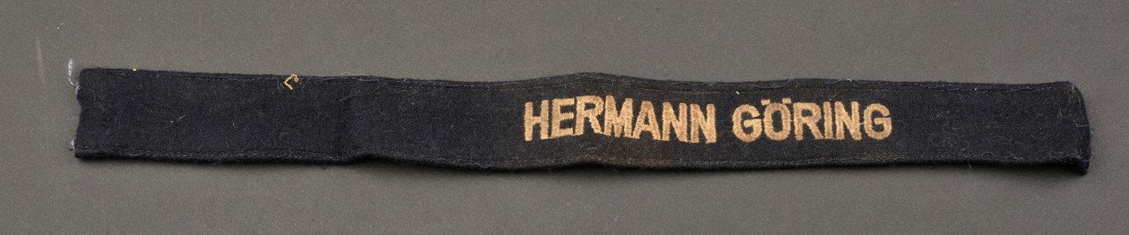 Bande de bras HG. Hermann Goring cufftittle.: Bande de bras Hermann Goring. Bande de manche en coton avec texte tisse machine. Modele pour le Fallschirm Panzer Korps Hermann Goring. Longueur 35,5 cm. Visiblement demontee d un uniforme, incomplete