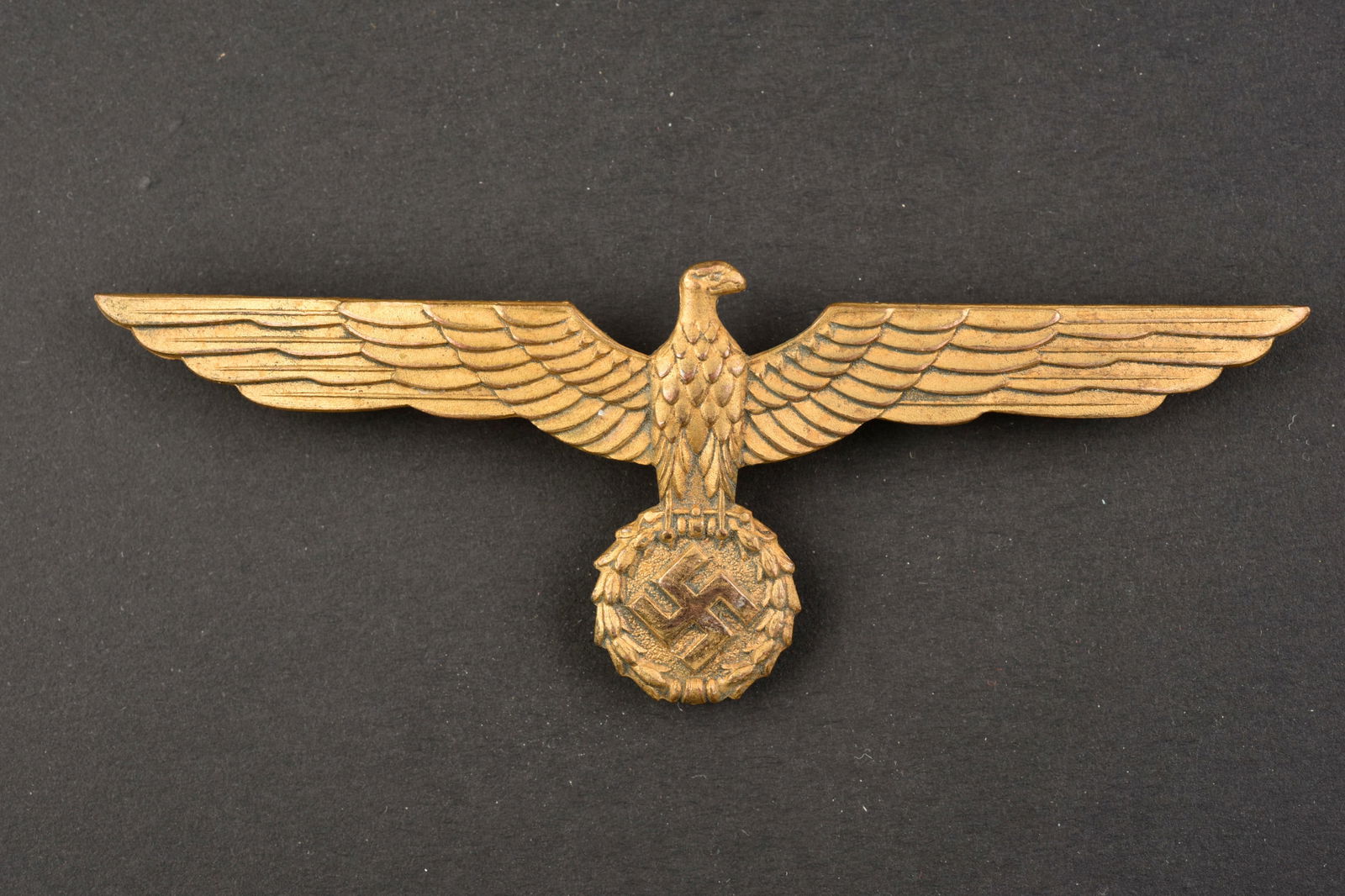Aigle de poitrine KM. Chest eagle KM.: Aigle de poitrine de la Kriegsmarine. Modele pour poitrine. En metal. Couleur or a 90%. Attache complete. Sans marquages visibles. A noter une certaine usure et patine de la piece. Etat II+. Kriegsmar