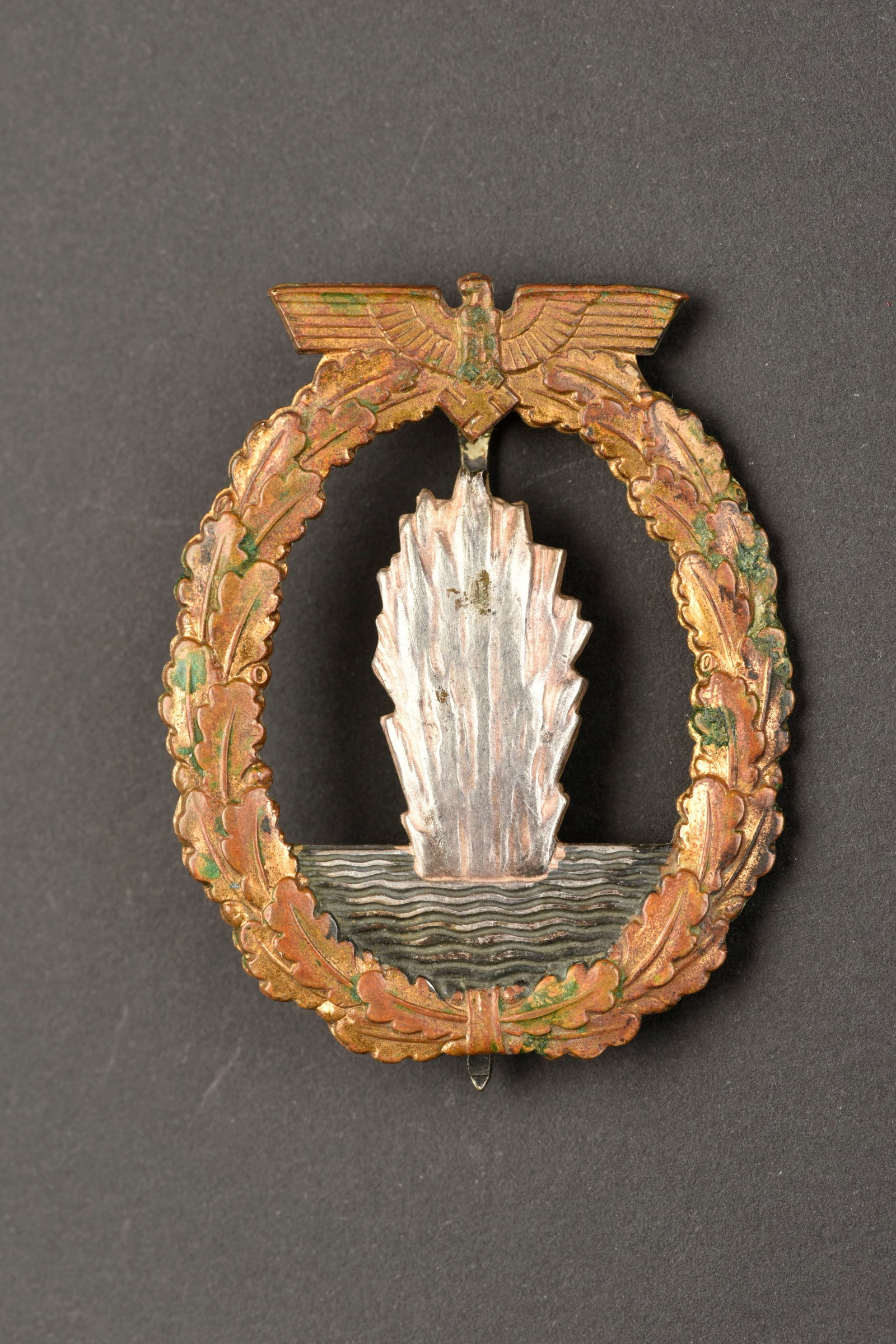 Insigne de mouilleurs de mine KM. KM mine-wetter badge.: Insignes des mouilleurs de mine de la Kriegsmarine. En metal. Couleur or a 10%, couleur argent a 80%. Attache complete. Marquages Fec Otto Placzek Berlin Ausf Schwerin Berlin. A noter une certaine usu