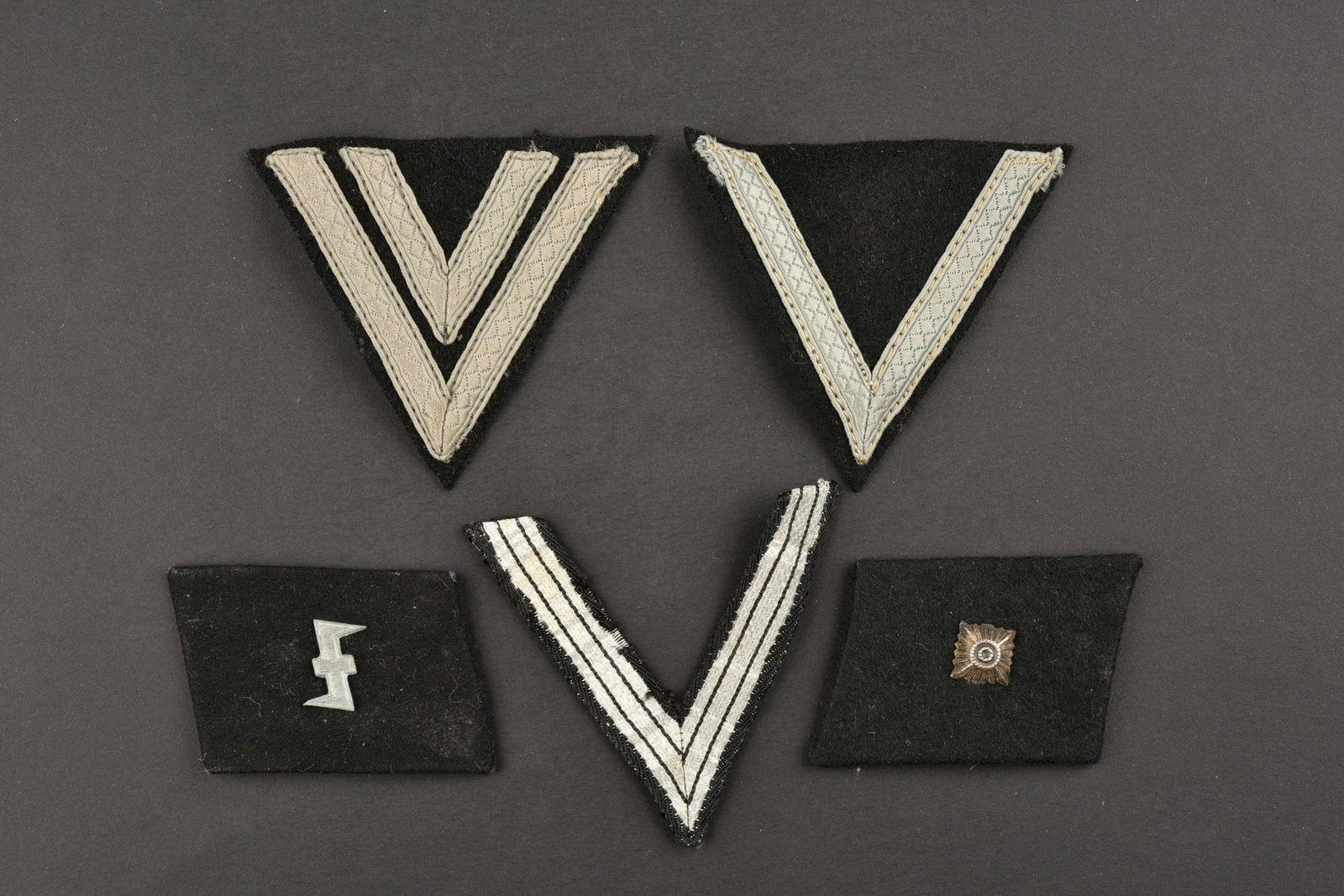 Insignes SS. SS insignia.: Insignes SS. Comprenant trois grades de manche de la SS. Une paire de pattes de col, avec insignes metalliques. L authenticite des pattes de col n est pas garantie. A noter une certaine usure et patin