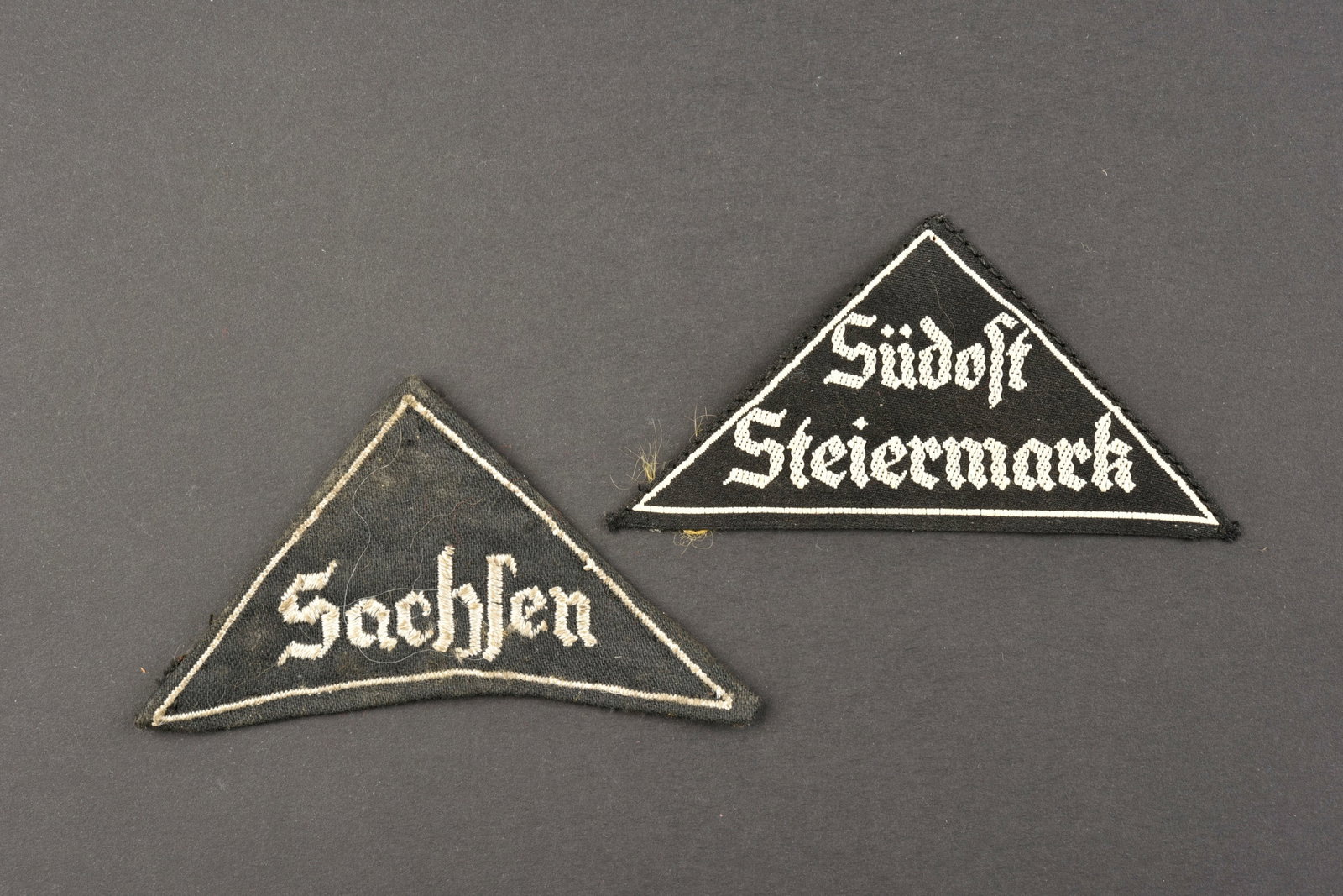 Triangles de bras BDM. BDM arm triangles.: Triangles de bras BDM. Comprenant un triangle de bras, brode blanc sur fond noir, marque Sudost Steiermark, etiquette RZM numero 400579, code fabricant M4/213. Un triangle de bras, brode blanc sur fon