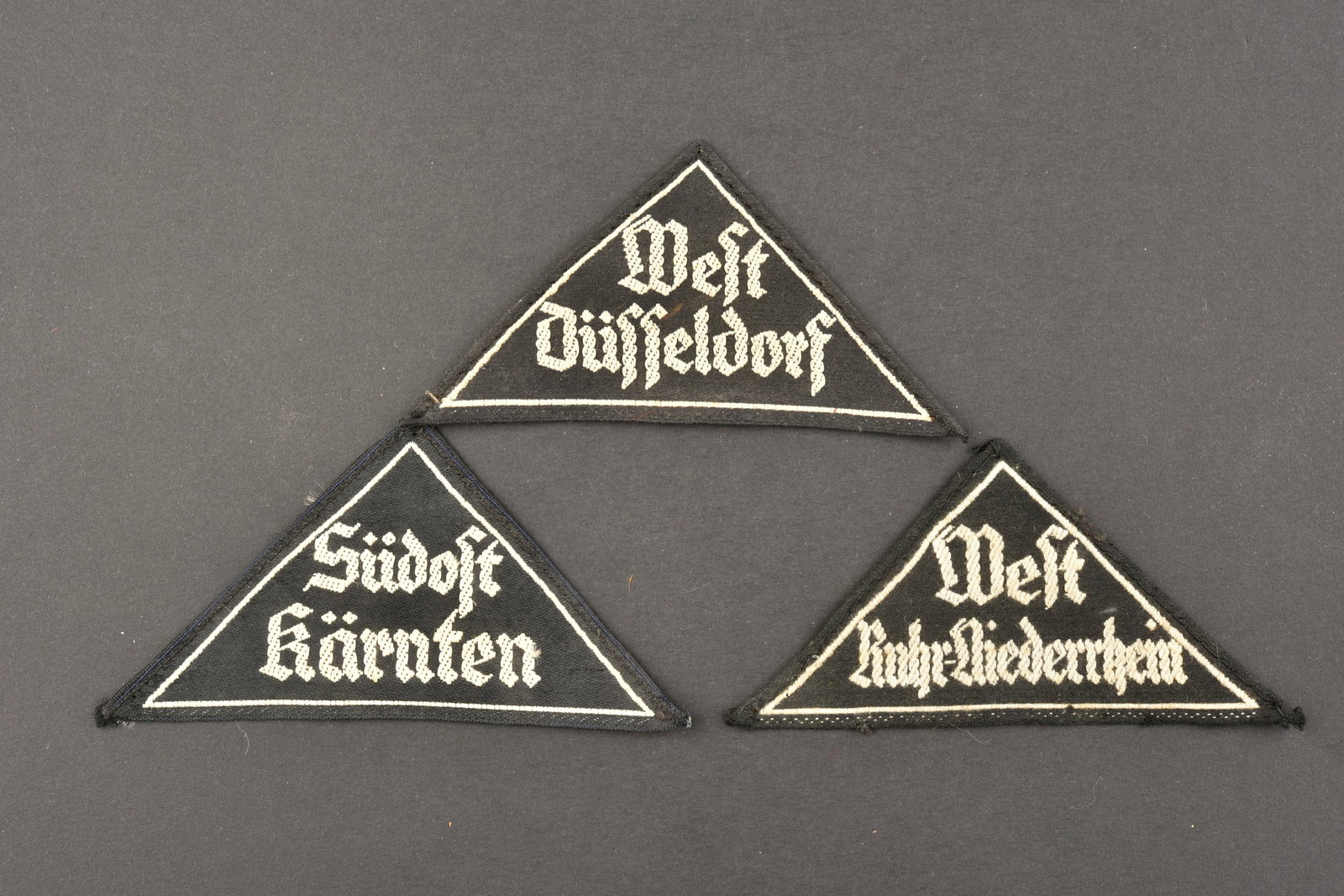 Triangles de bras BDM. BDM arm triangles.: Triangles de bras BDM. Comprenant un triangle de bras tisse blanc sur fond noir, marque West Dusseldorf, etiquette RZM numero 022197, code fabricant M4/931. Un triangle de bras tisse blanc sur fond no