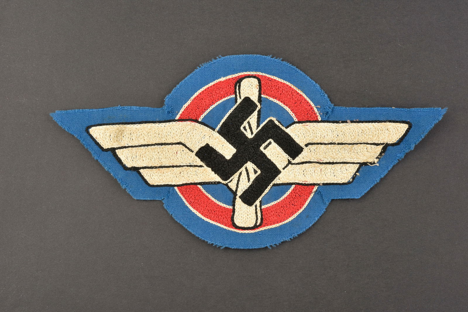 Insigne de maillot de sport DLV. DLV sports jersey badge.: Insigne de maillot de sport DLV. Modele brode sur fond en tissu bleu roi. Predecoupe, mais jamais monte. A noter une certaine usure et patine de la piece, ainsi que quelques traces de colle. Etat II+.