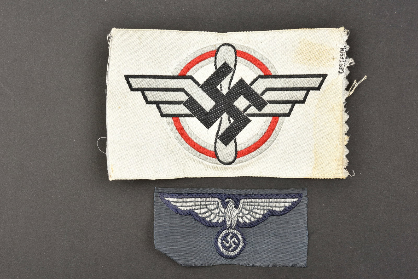 Insignes DLV. DLV badges.: Insignes DLV. Comprenant un aigle de coiffure Bevo, jamais monte. Un insigne de poitrine brode du DLV, sur fond en tissu blanc, marque Ges Gesch. A noter une certaine usure et patine des pieces, ainsi