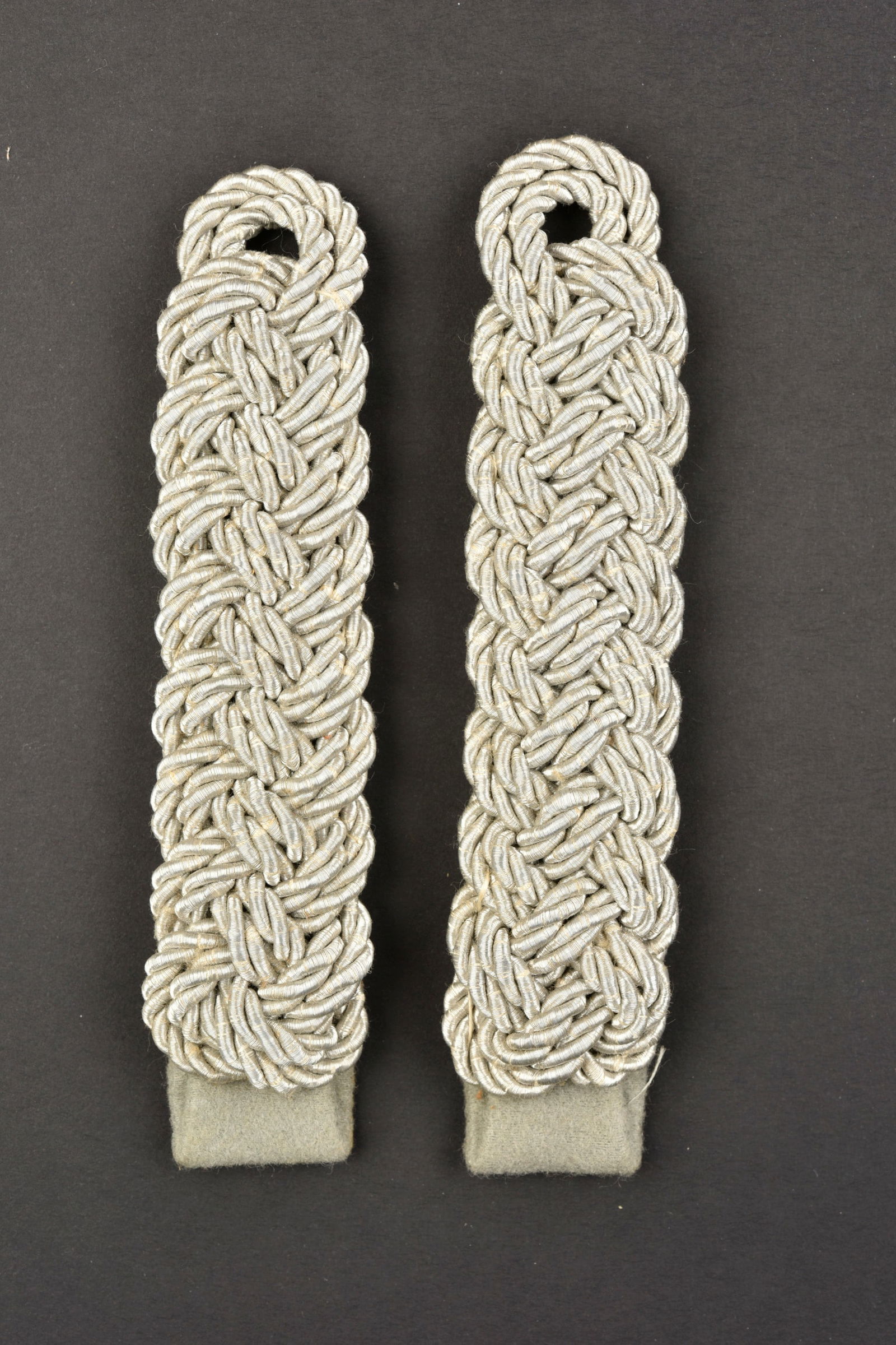 Pattes d'epaule DRK. DRK shoulder straps: Pattes d'epaule DRK. Au grade de DRK-Feldfuhrer. Paire homogene couleur argent, fond en drap gris. A noter une certaine usure et patine des pieces. Etat II+. DRK shoulder straps. To the rank of DRK-Fe
