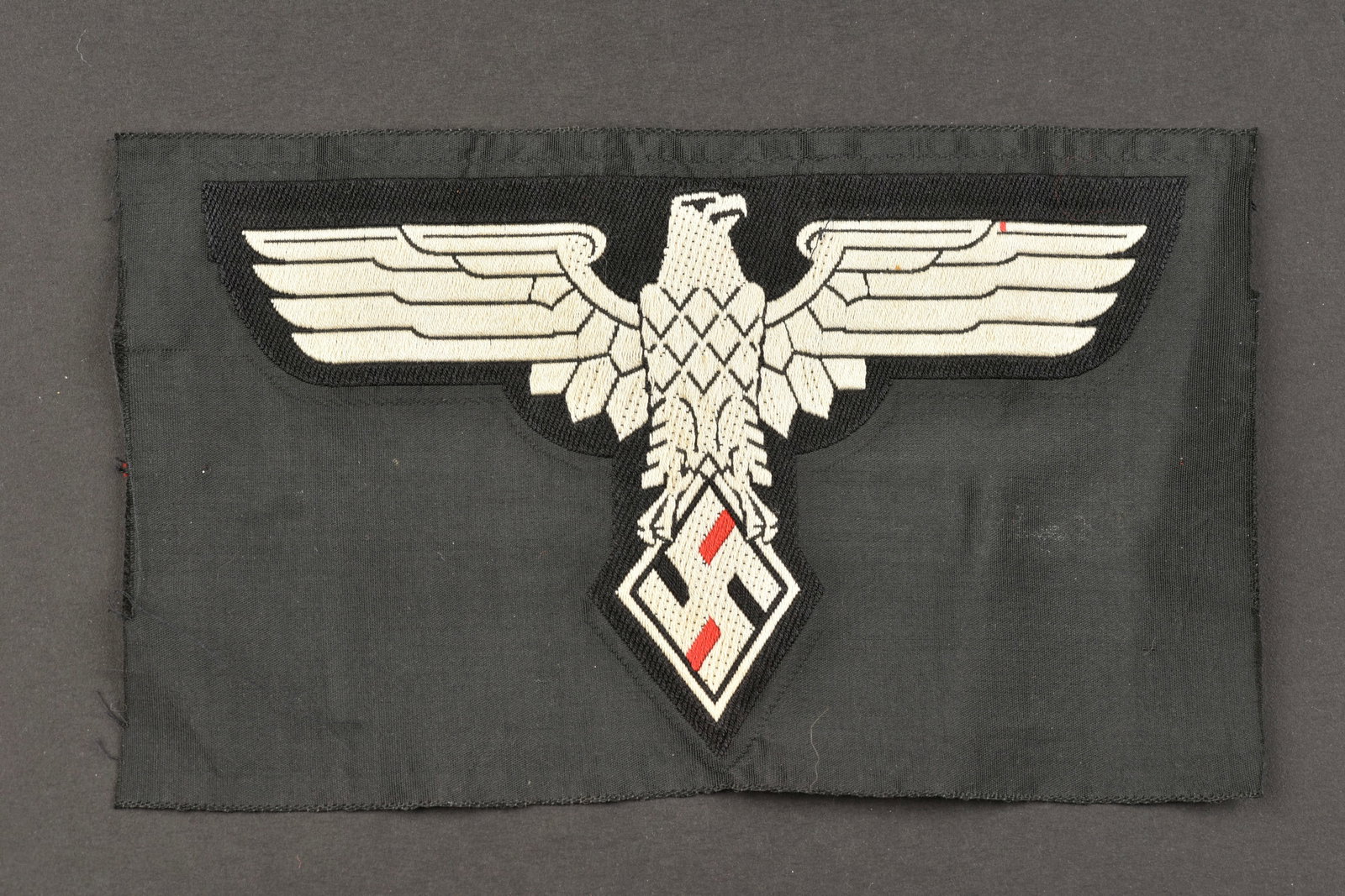 Insigne de maillot de sport etudiants du Reich. Reich student sports jersey badge.: Insigne de maillot de sport de l'association des etudiants du Reich. Modele d'aigle tisse sur fond en tissu noir, jamais monte. A noter une certaine usure et patine de la piece, ainsi que quelques tra