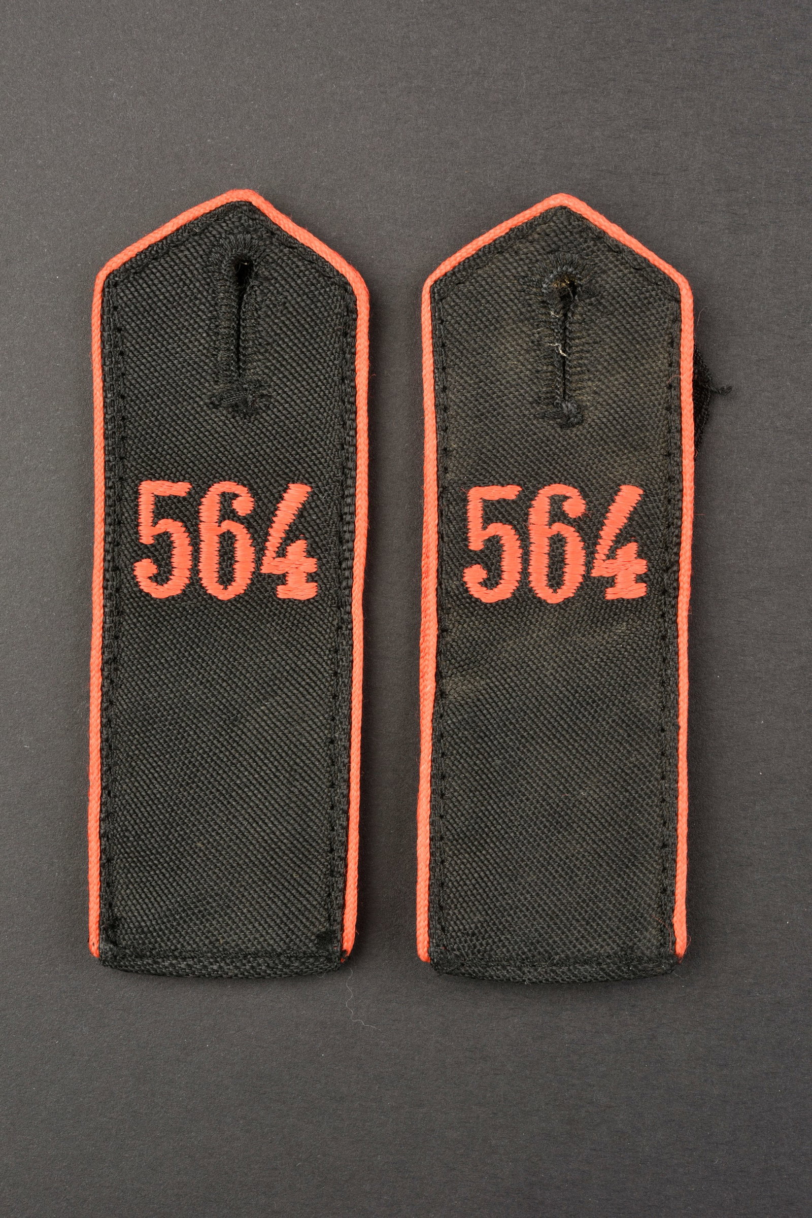 Pattes d'epaule HJ. HJ shoulder straps.: Pattes d'epaule HJ. Bann 564 Villach. Paire homogene en tissu noir. Lisere rouge. Lettrage 564 brode en fil rouge. Jamais monte. Etiquette RZM numeros 123430 et 122911, code fabricant 86. A noter une 