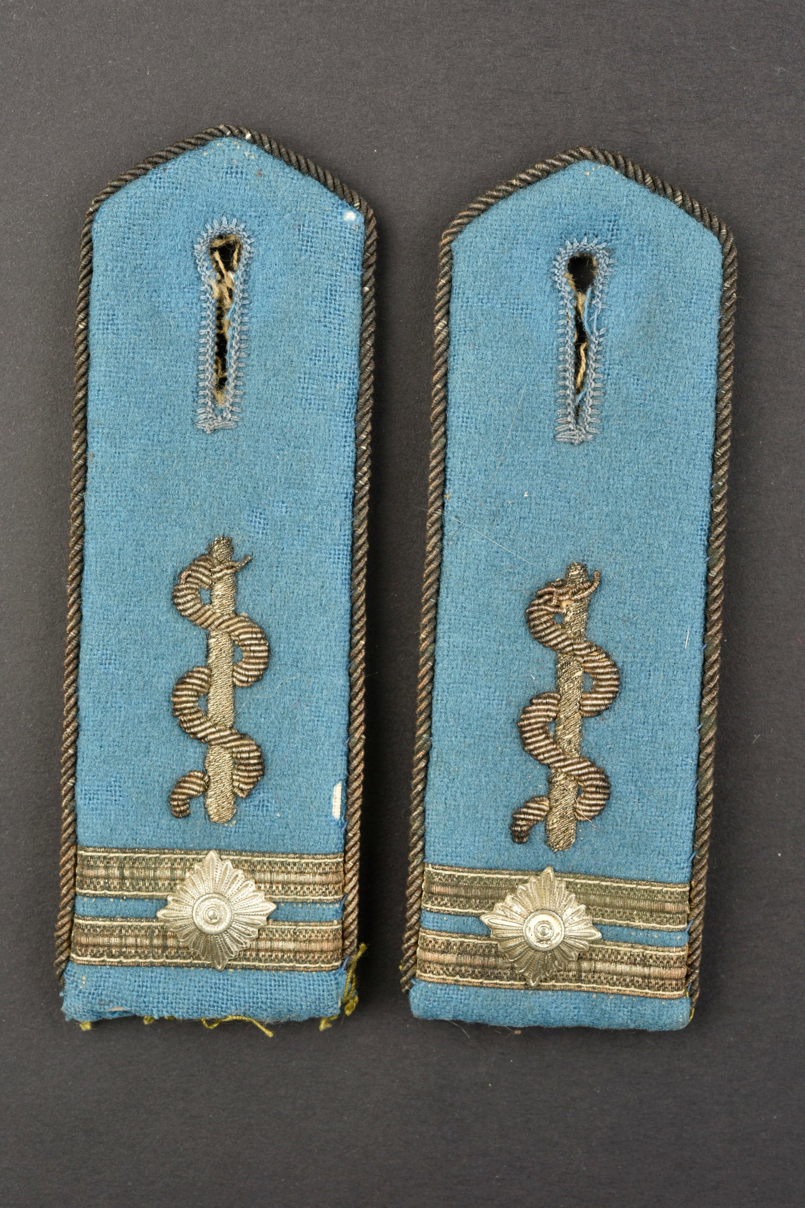 Pattes d'epaule HJ. HJ shoulder straps.: Pattes d'epaule Hitlerjugend. Paire homogene en drap bleu. Lisere et caducee en cannetille doree. Grade represente par deux galon or et un clou de grade. Dos de la piece double en tissu beige. Reste d