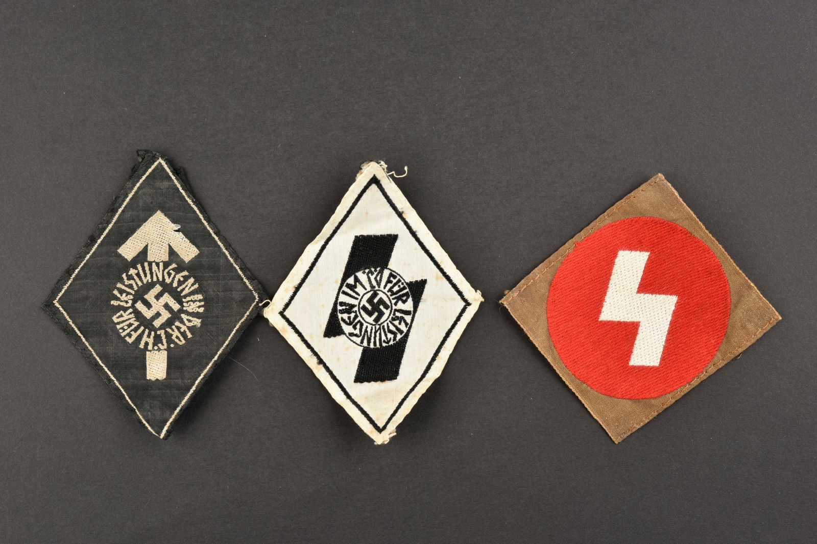 Insignes HJ. HJ insignia.: Inignes de la Hitlerjugend. Comprenant un insigne en tissu marque Fur Leistungen im DJ, visiblement demonte d'un uniforme. Un insigne tissu Fur Leistungen in der HJ, demonte d'une vareuse. Un insigne