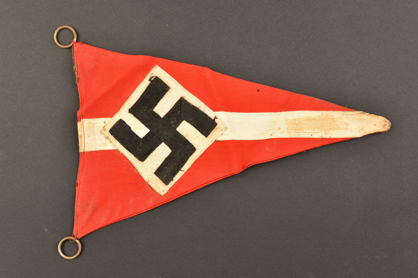 Fanion HJ. HJ pennant.: Fanion Hitlerjugend. En tissu coton rouge et blanc. Insigne allemand rapporte. Biface. Deux anneaux de fixation. Dimensions 14,5 x 22 cm. A noter une certaine usure et patine de la piece, ainsi que de