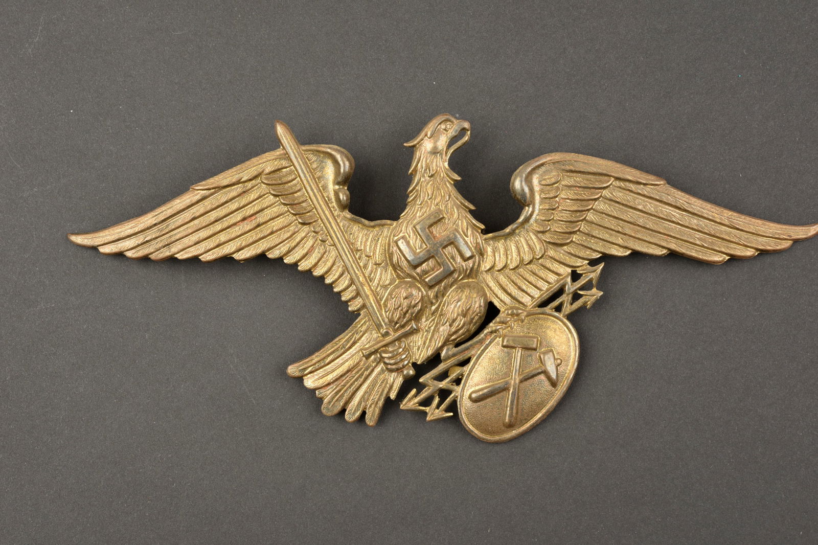 Aigle de shako mineur. Miner's shako eagle.: Aigle de shako des mineurs du Reich. En metal embouti couleur bronze. Deux attache sont manquantes. Beaux decors en relief. A noter une certaine usure et patine de la piece. Etat II+. Reich miners' sh