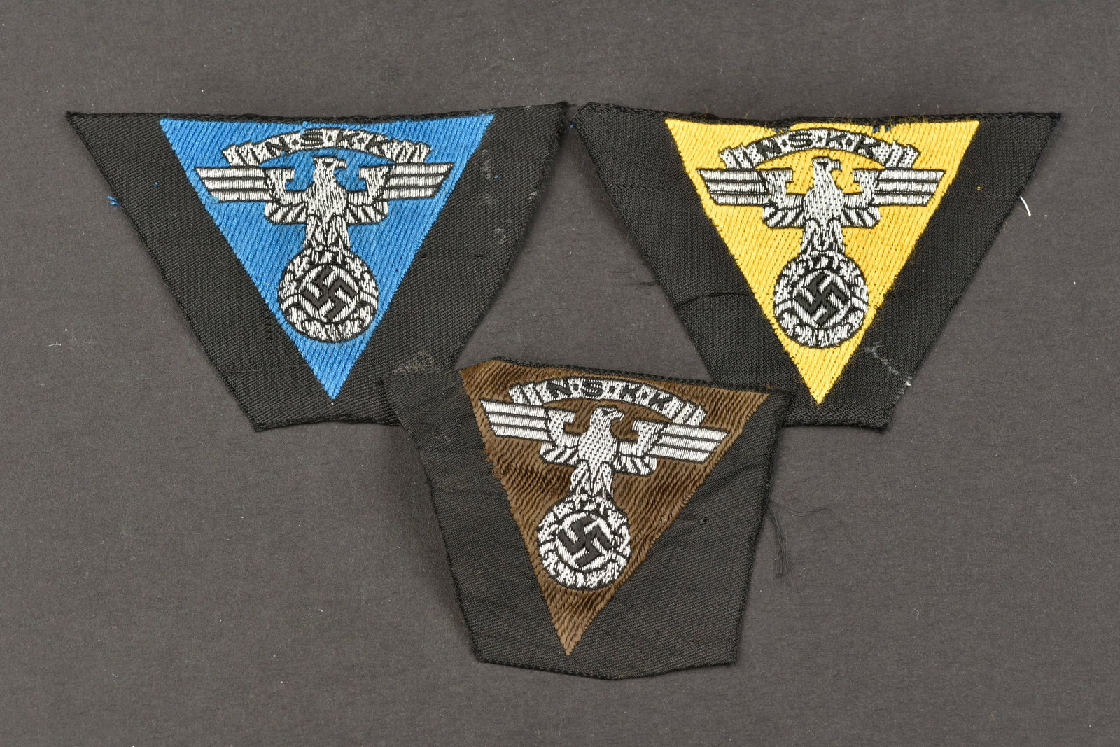 Aigles de calot NSKK. NSKK cap badges.: Aigles de calot NSKK. Comprenant un aigle de calot Bevo, sur fond noir, jamais monte, couleur marron du Motorgruppe Westmark. Un insigne de calot Bevo, sur fond noir, jamais monte, couleur jaune du Mo
