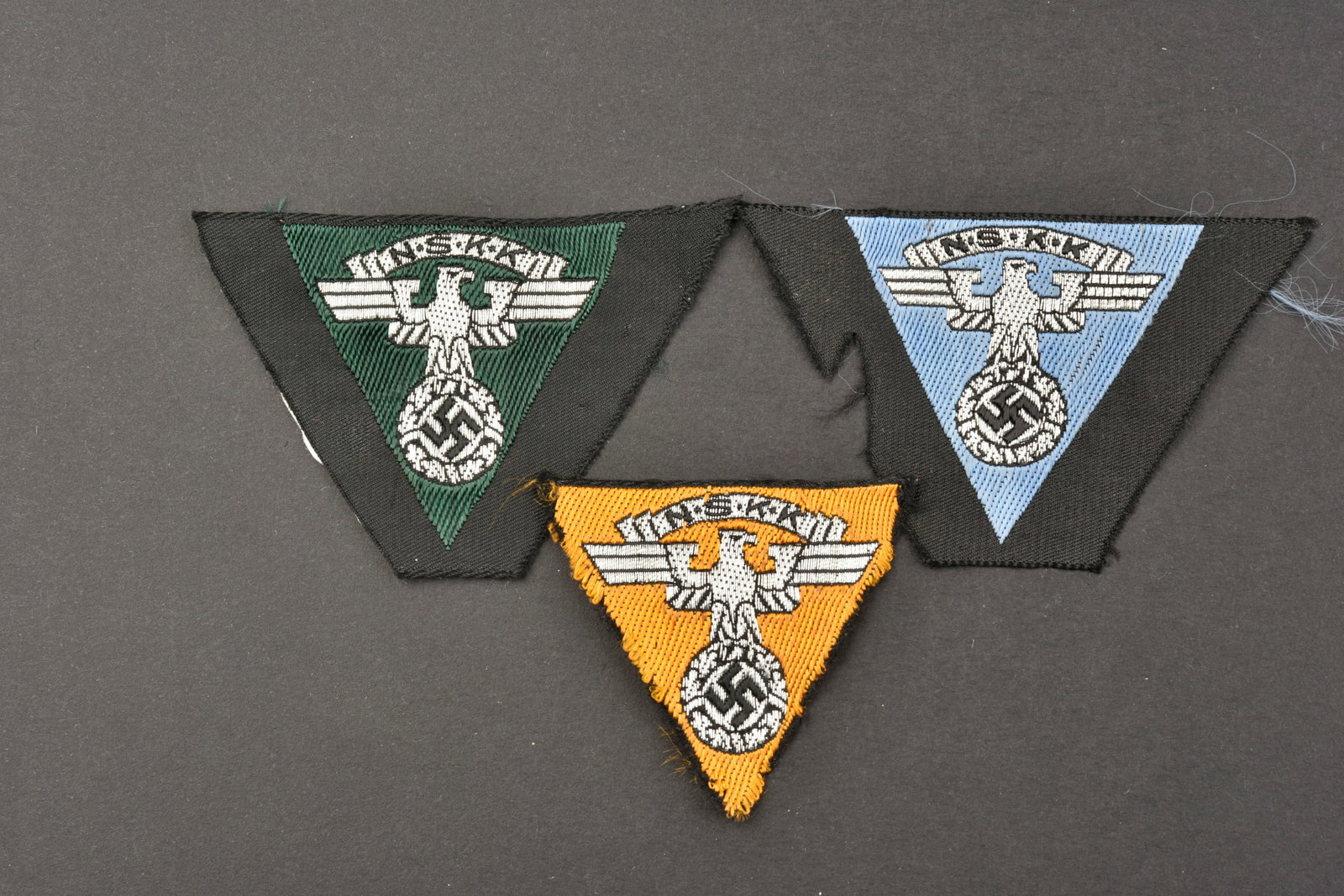 Aigles de calot NSKK. NSKK cap badges.: Aigles de calot NSKK. Comprenant un aigle de calot Bevo, sur fond noir, jamais monte, couleur vert fonce du Motorgruppe Nordsee. Un insigne de calot Bevo, sur fond noir, visiblement demonte d'une coif