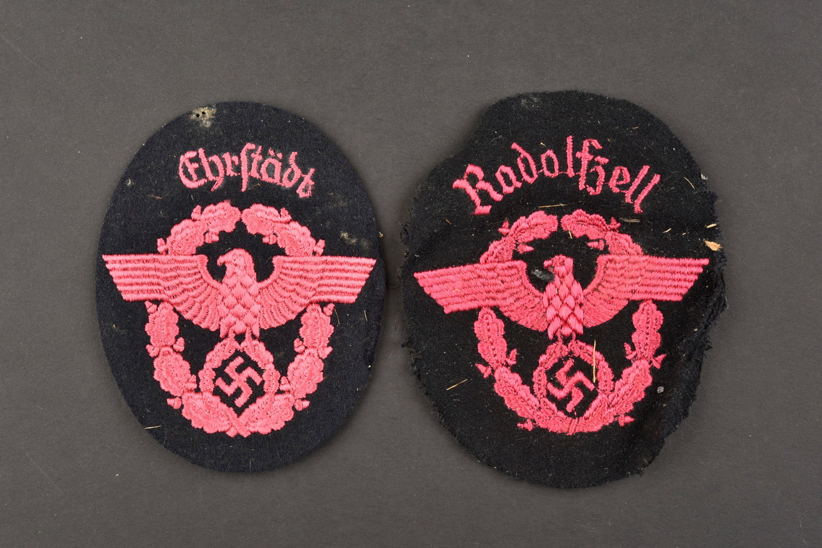 Insignes de manche de pompier. Fireman's sleeve badges.: Insignes de manche de pompier. Comprenant un insigne en drap noir, visiblement demonte d'une vareuse, broderie rose, marquages Radolfzell (bodensee). Un insigne de manche en drap bleu marine, broderie