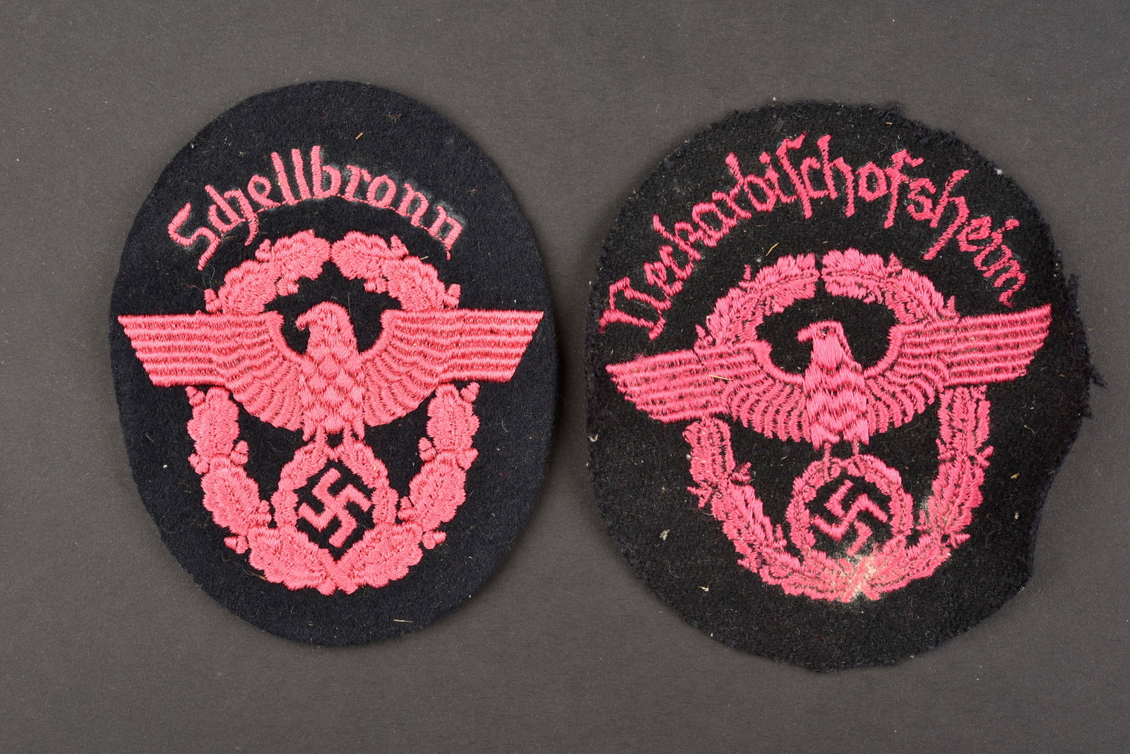 Insigne des pompier. Fireman's sleeve badges.: Insignes des pompiers du Reich. Comprenant un insigne de manche en drap noir et broderie rose, marquages Neckarbischofsheim, traces de colle au dos. Un insigne de manche en drap noir et broderie rose,