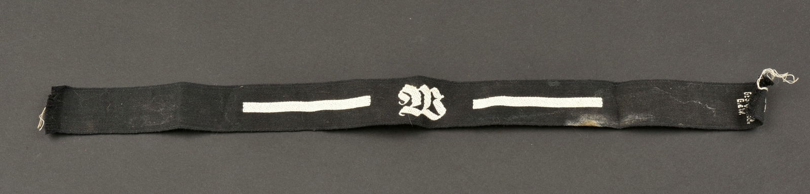 Bande de bras RAD. RAD cuff tittle.: Bande de bras RAD. En tissu noir, avec lisere blanc. Lettre W tissee. Longueur 36 cm. Marquages RADJ Ges Gesch. A noter une certaine usure et patine de la piece, ainsi que des taches. Etat II+. RAD ar