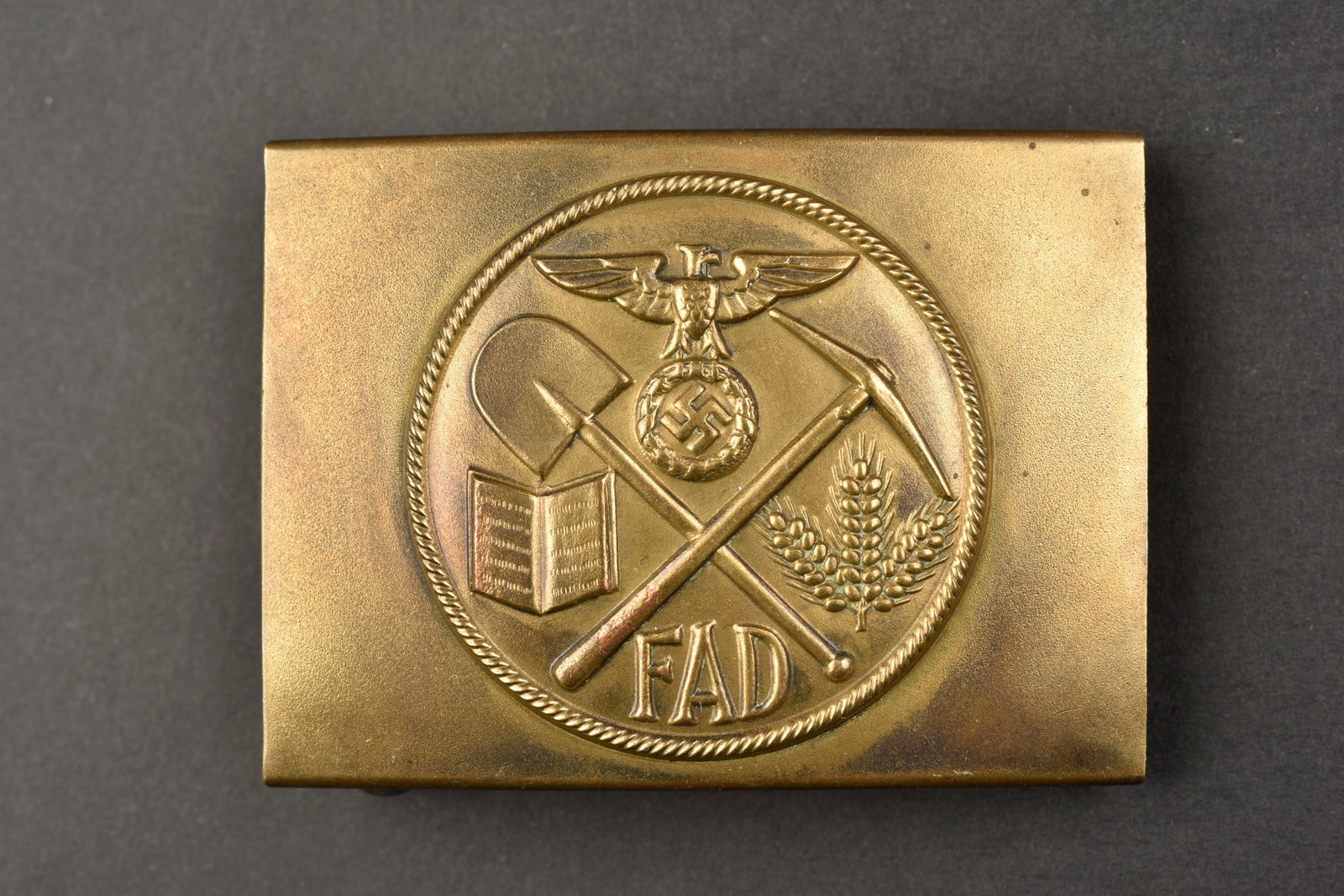 Boucle de ceinturon FAD. FAD belt buckle.: Boucle de ceinturon FAD. En laiton, beaux decors en relief, marquages FAD. Les deux ardillons sont presents. Sans marquages visibles. A noter une certaine usure e patine de la piece. L'authenticite de