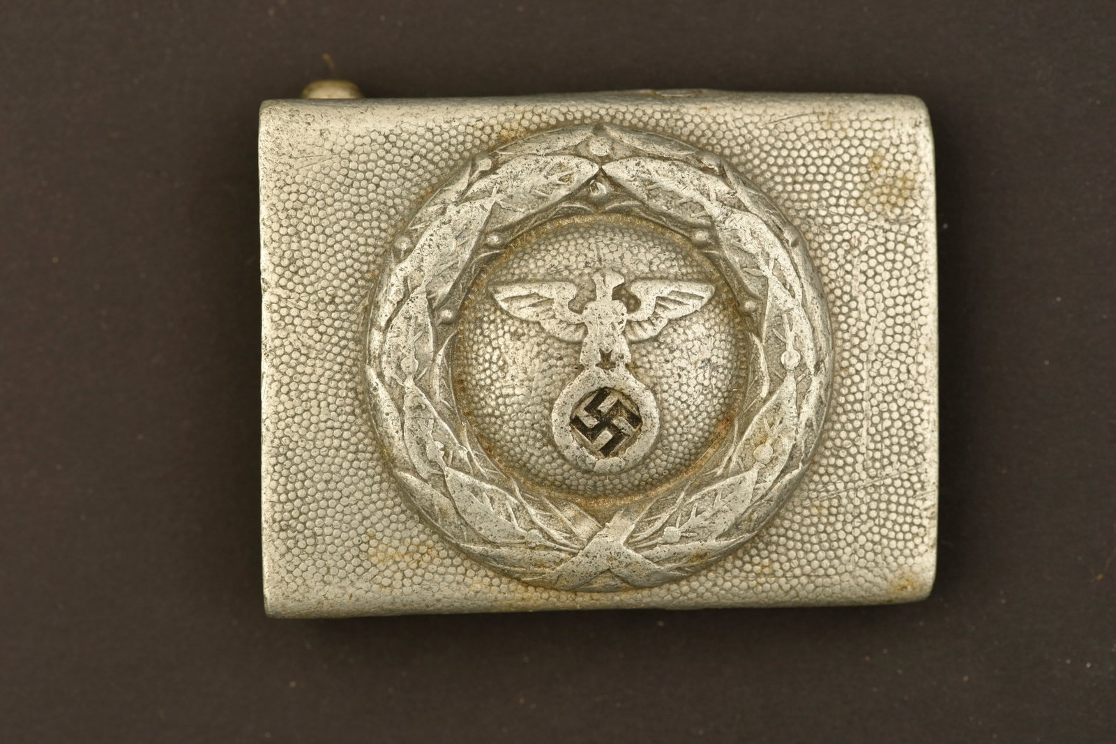 Boucle de RSLV. RSLV belt buckle.: Boucle de ceinturon du RSLV. En aluminium grenele. Bel aigle en relief. Couleur nationale dans sa couleur noire d'origine. Sans marquages visibles. Couleur argent a 80%. Boucle a deux ardillons comple