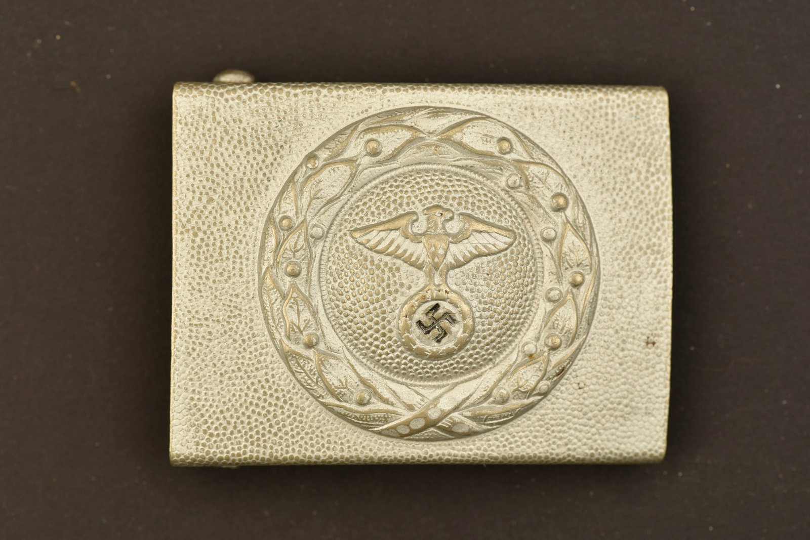Boucle de ceinturon RLB. RLB belt buckle.: Boucle de ceinturon RLB. En metal grenele. Fabrication en une seule partie. Couleur noir de la croix gammee a 65%. Ardillons complets. Sans marquages visibles. A noter une certaine usure et patine de 