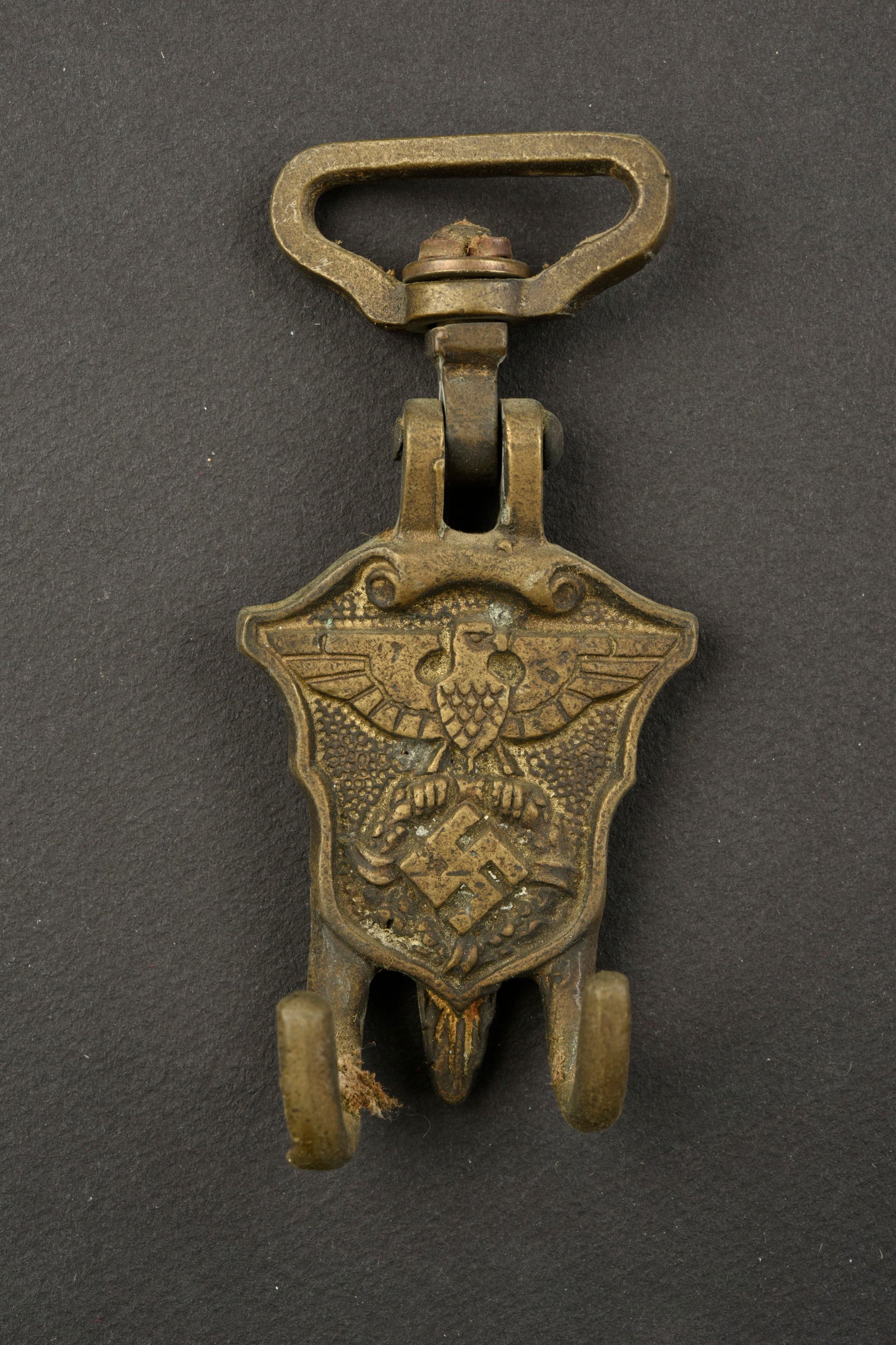 Porte tambour SA. SA drum door.: Porte tambour SA. Petit modele. En metal, couleur doree a 60%. Bel aigle et insigne national en relief. Les crochets de support du tambour sont presents. Sans marquages visibles. A noter une certaine